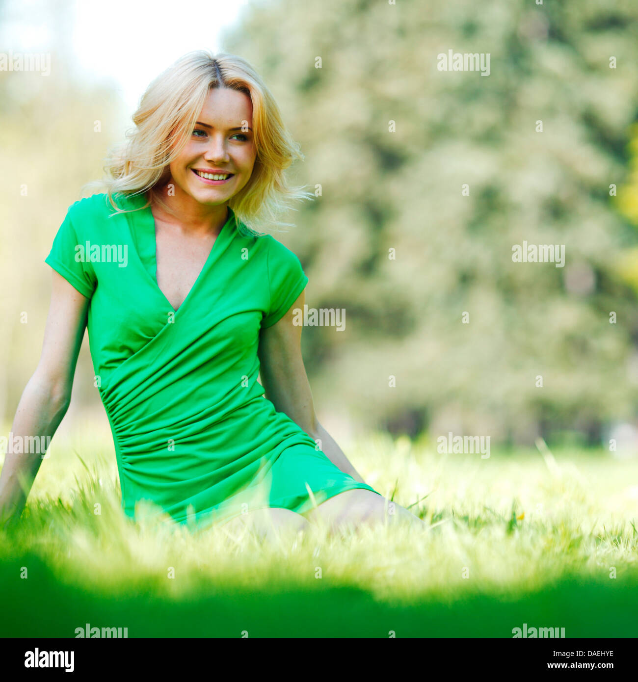 Happy young woman sitting on grass Stock Photo - Alamy