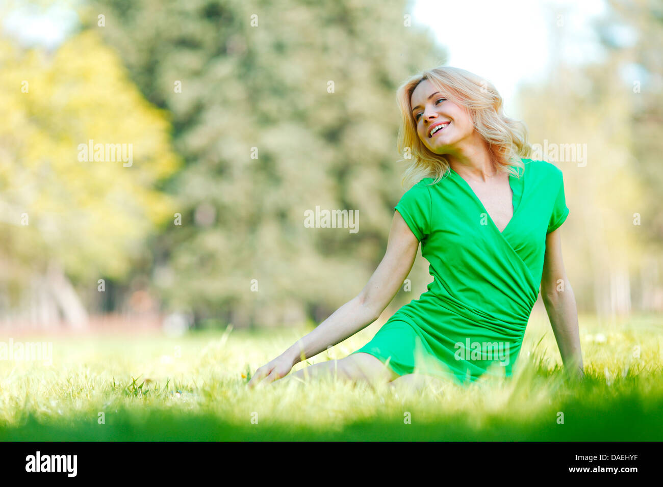 Happy young woman sitting on grass Stock Photo - Alamy