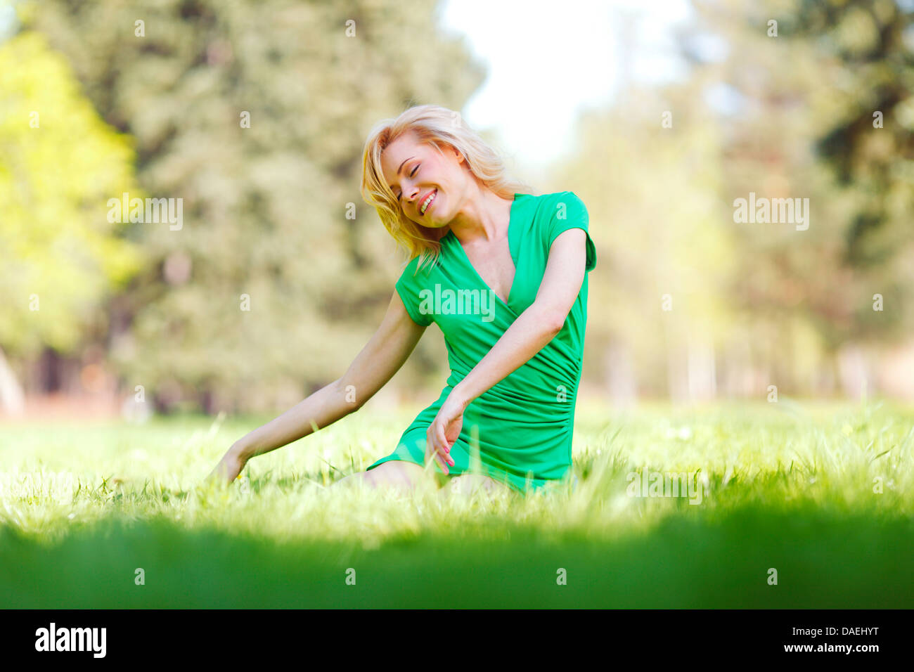 Happy young woman sitting on grass Stock Photo - Alamy