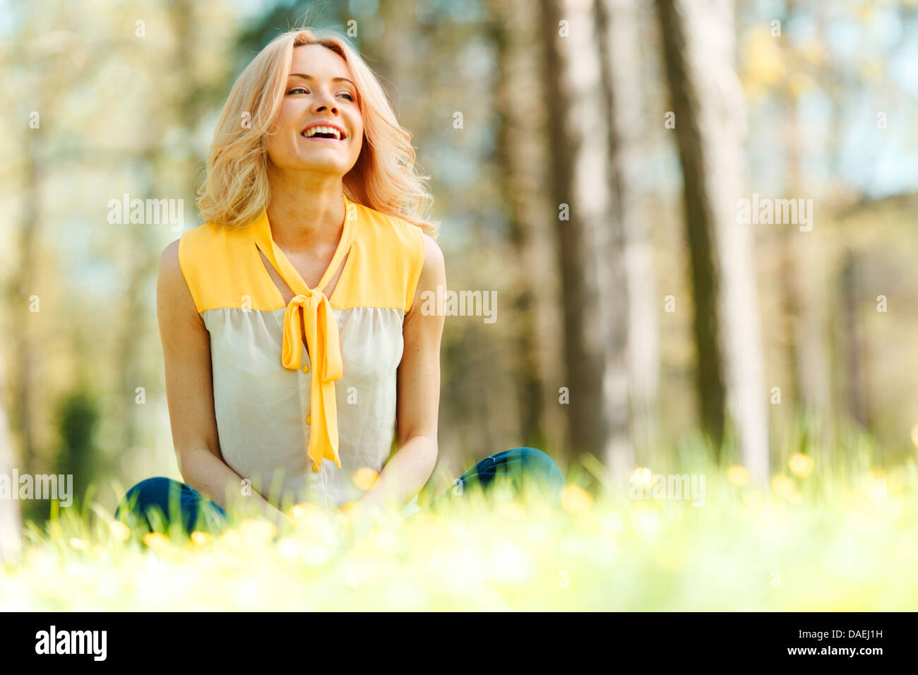 Beautiful happy young woman sitting on grass Stock Photo - Alamy