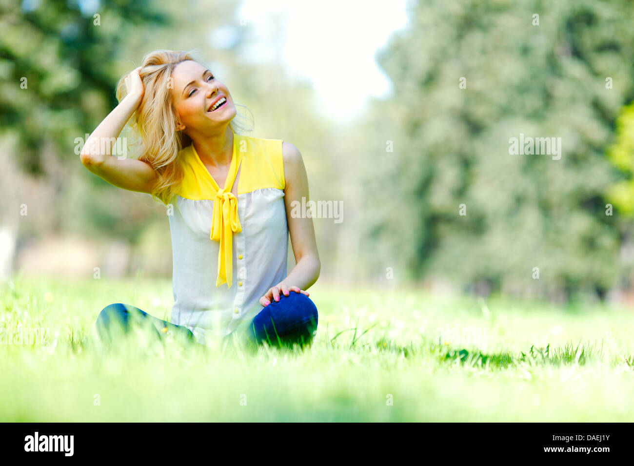 Beautiful happy young woman sitting on grass Stock Photo - Alamy