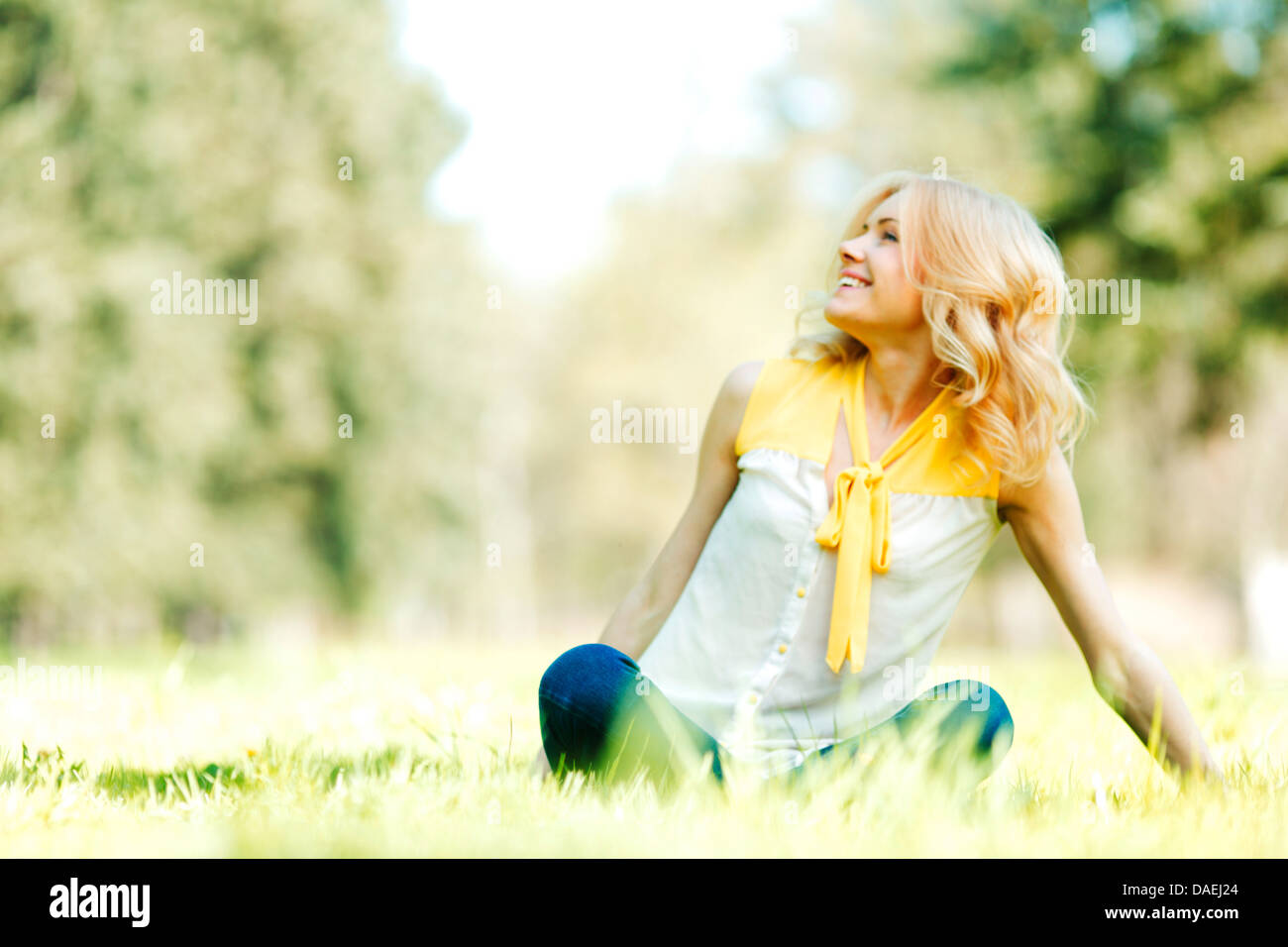 Beautiful happy young woman sitting on grass Stock Photo - Alamy