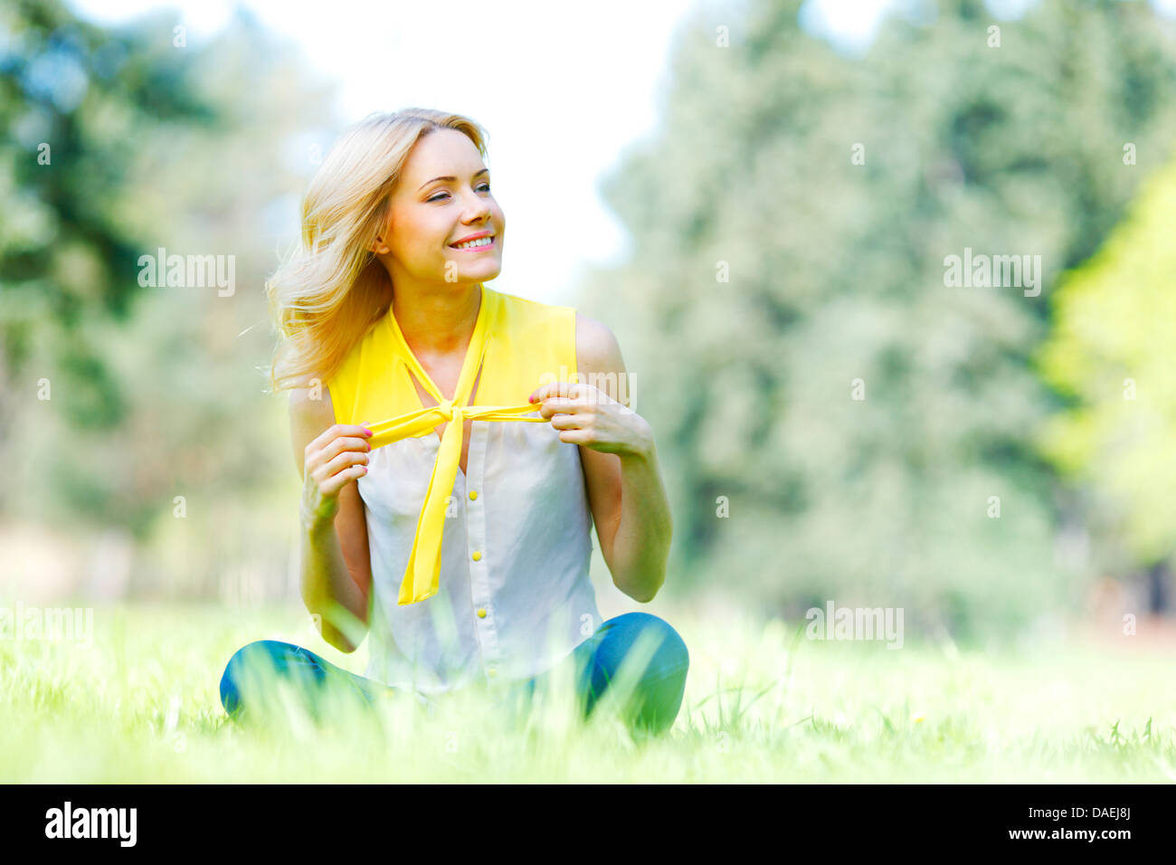 Beautiful happy young woman sitting on grass Stock Photo - Alamy