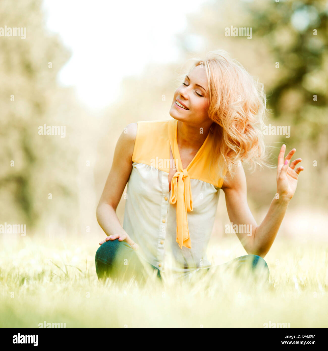 Beautiful happy young woman sitting on grass Stock Photo - Alamy