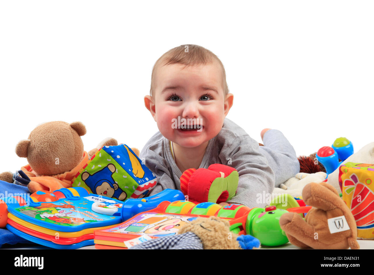 baby lying in a heap of playthings and crying Stock Photo