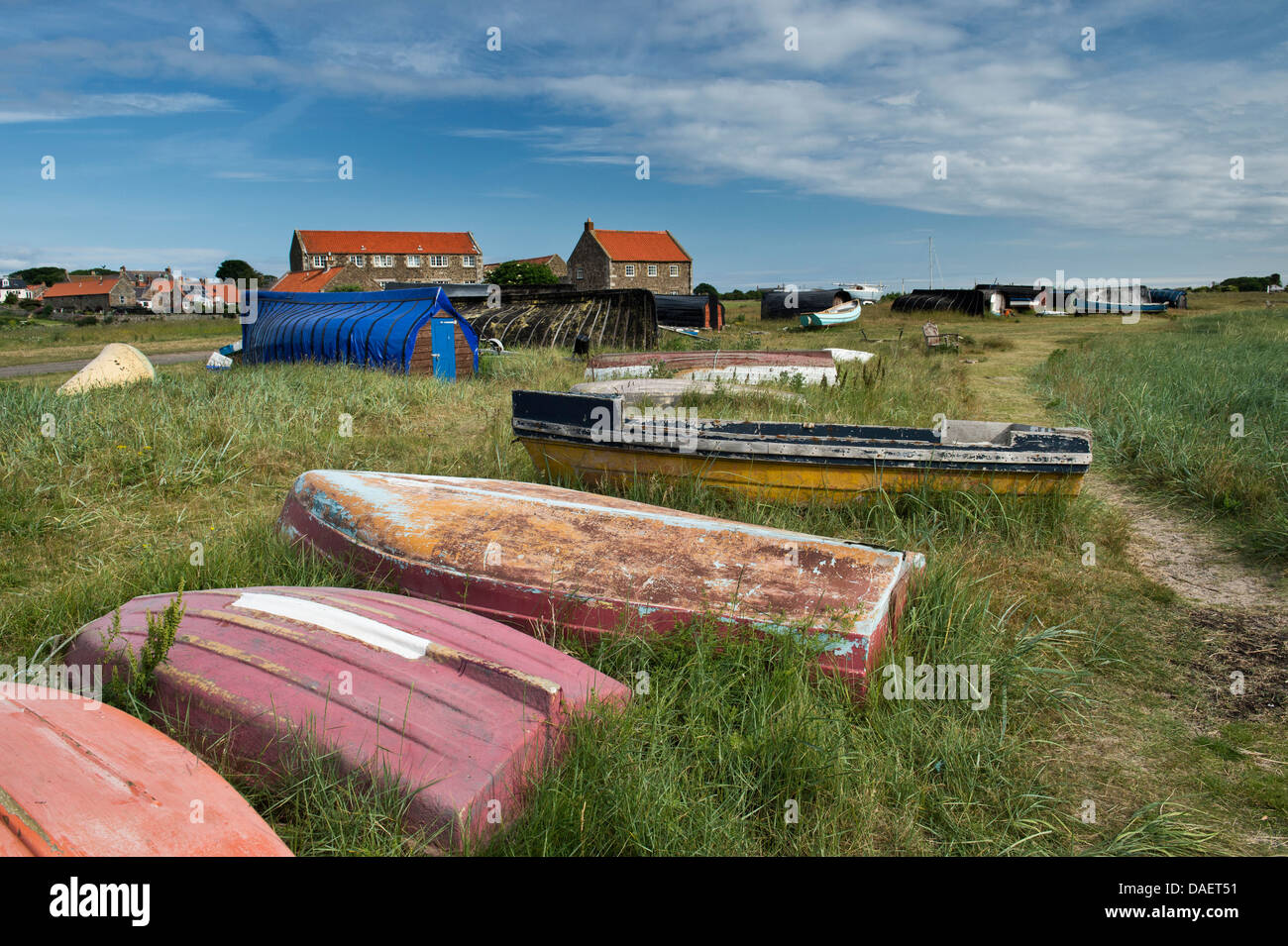 Boats and Herring boat sheds in front of houses in the harbour at Lindisfarne, Northumberland, England Stock Photo