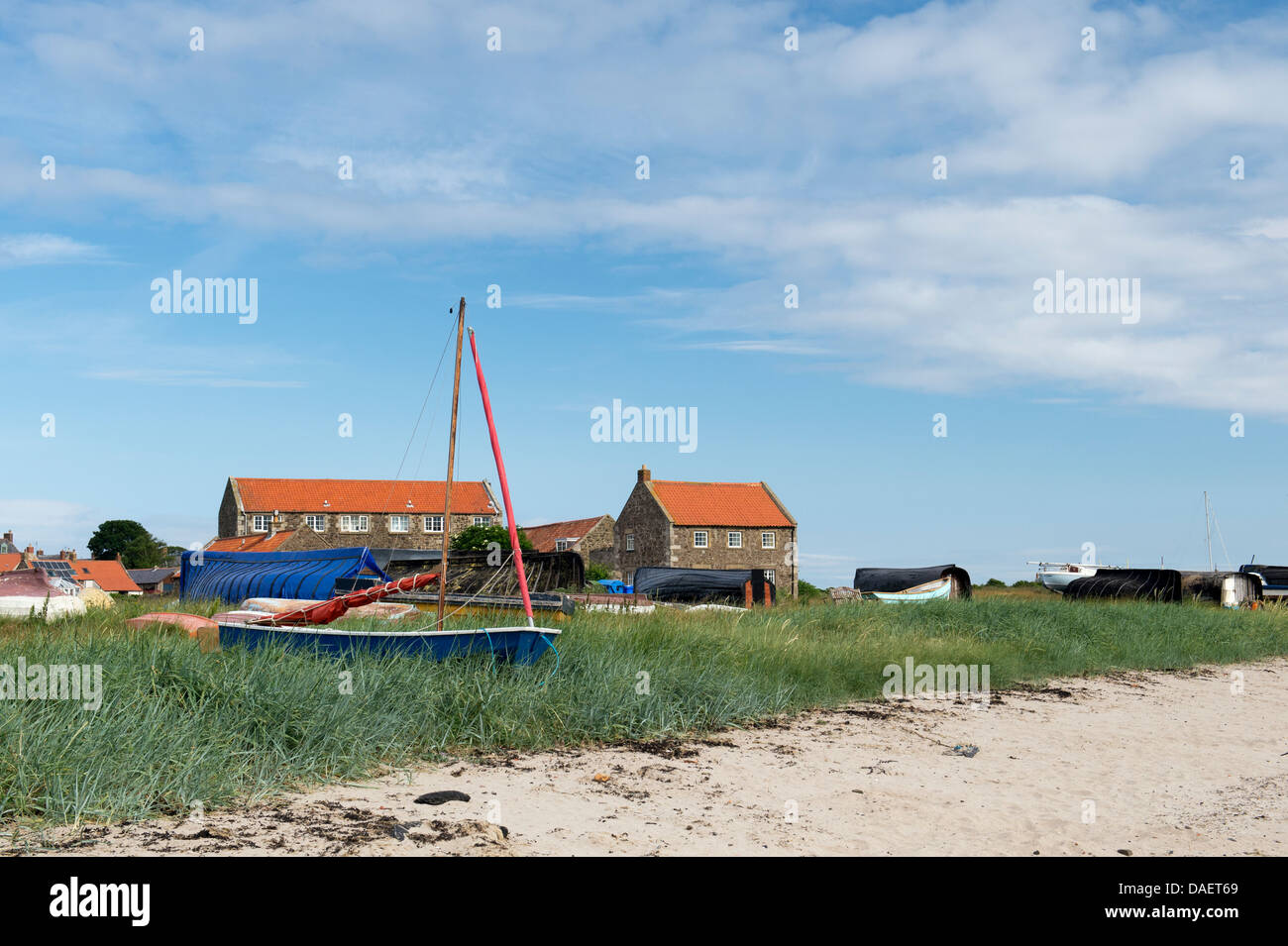 Boats and Herring boat sheds in front of houses in the harbour at Lindisfarne, Northumberland, England Stock Photo