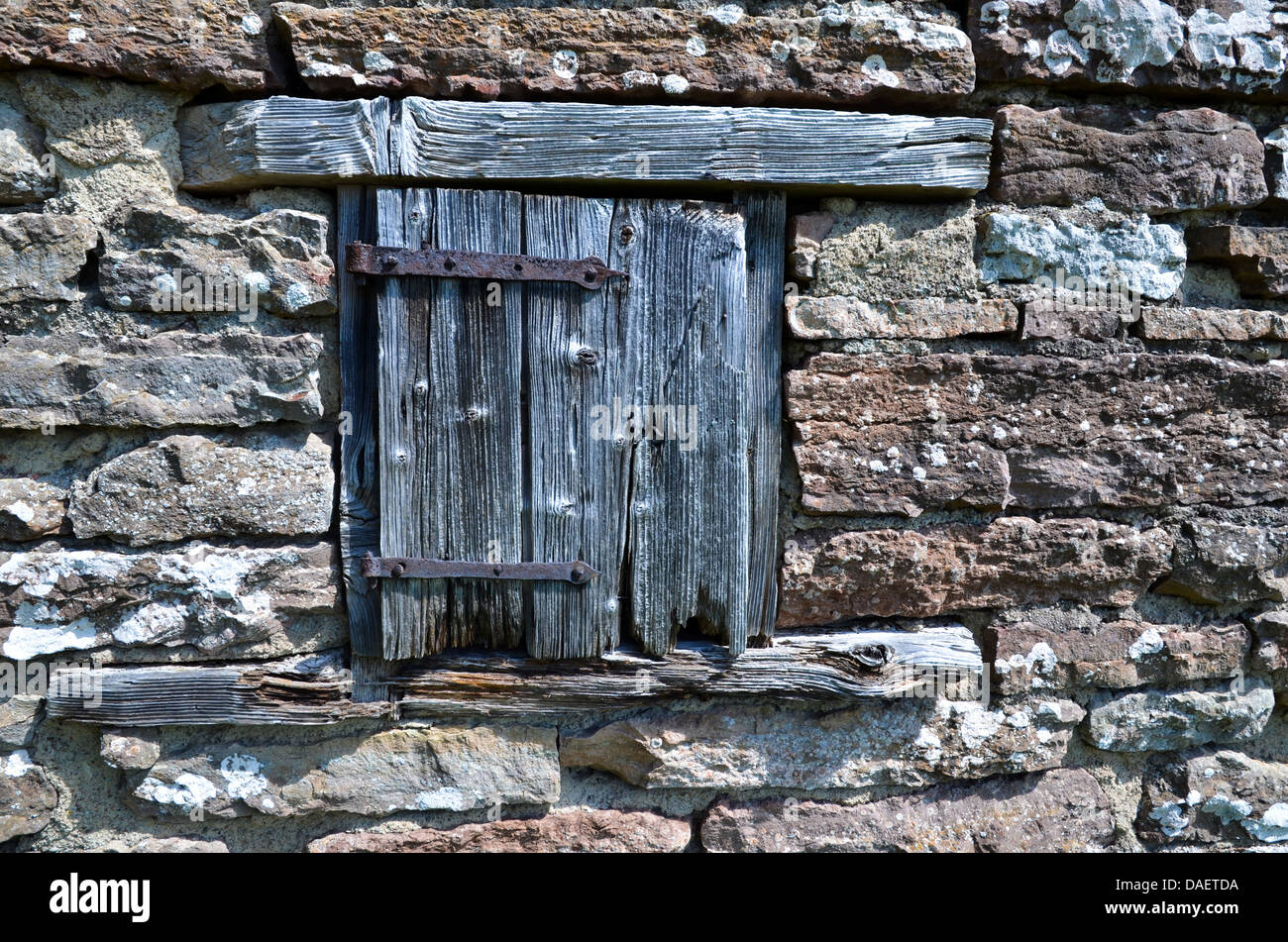 Weathered door at a window by an old brick wall. Stock Photo
