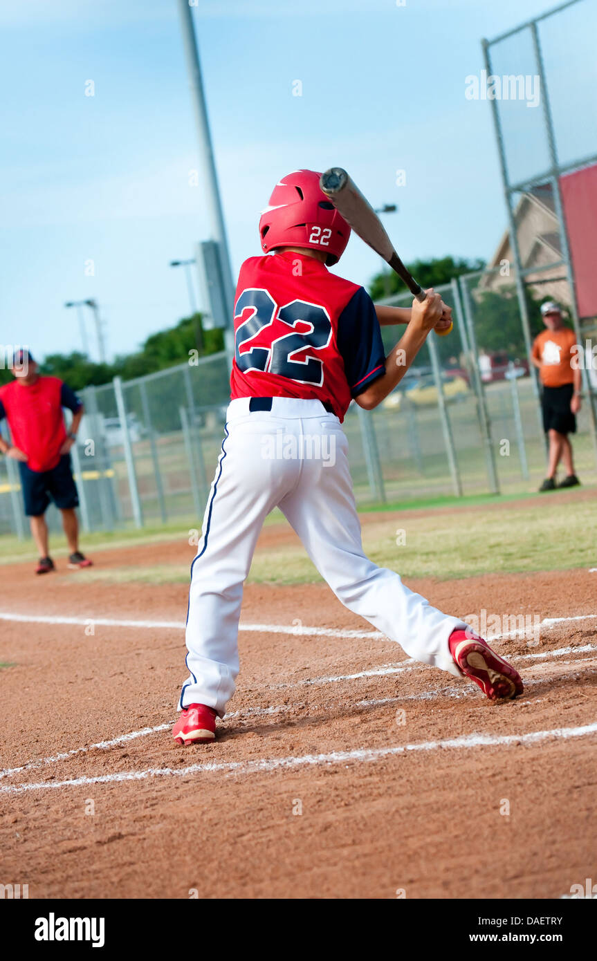 Young baseball kid swinging the bat during a game. Stock Photo