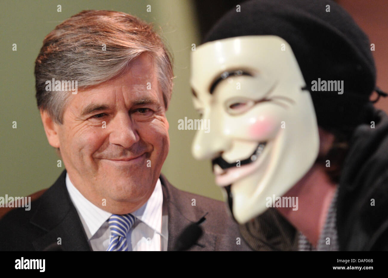 An Occupy activist wearing a Guy Fawkes mask interrupts Joseph Ackermann, CEO of Deutsche Bank, during his speech to the members' meeting of the Ehrbarer Kaufmann (Honorable Merchants) in Hamburg, Germany, 22 November 2011. Several activists of the Occupy movement disrupted the speech of the bank chief and stormed the podium at the chamber of commerce in Hamburg. Photo: MARCUS BRAN Stock Photo