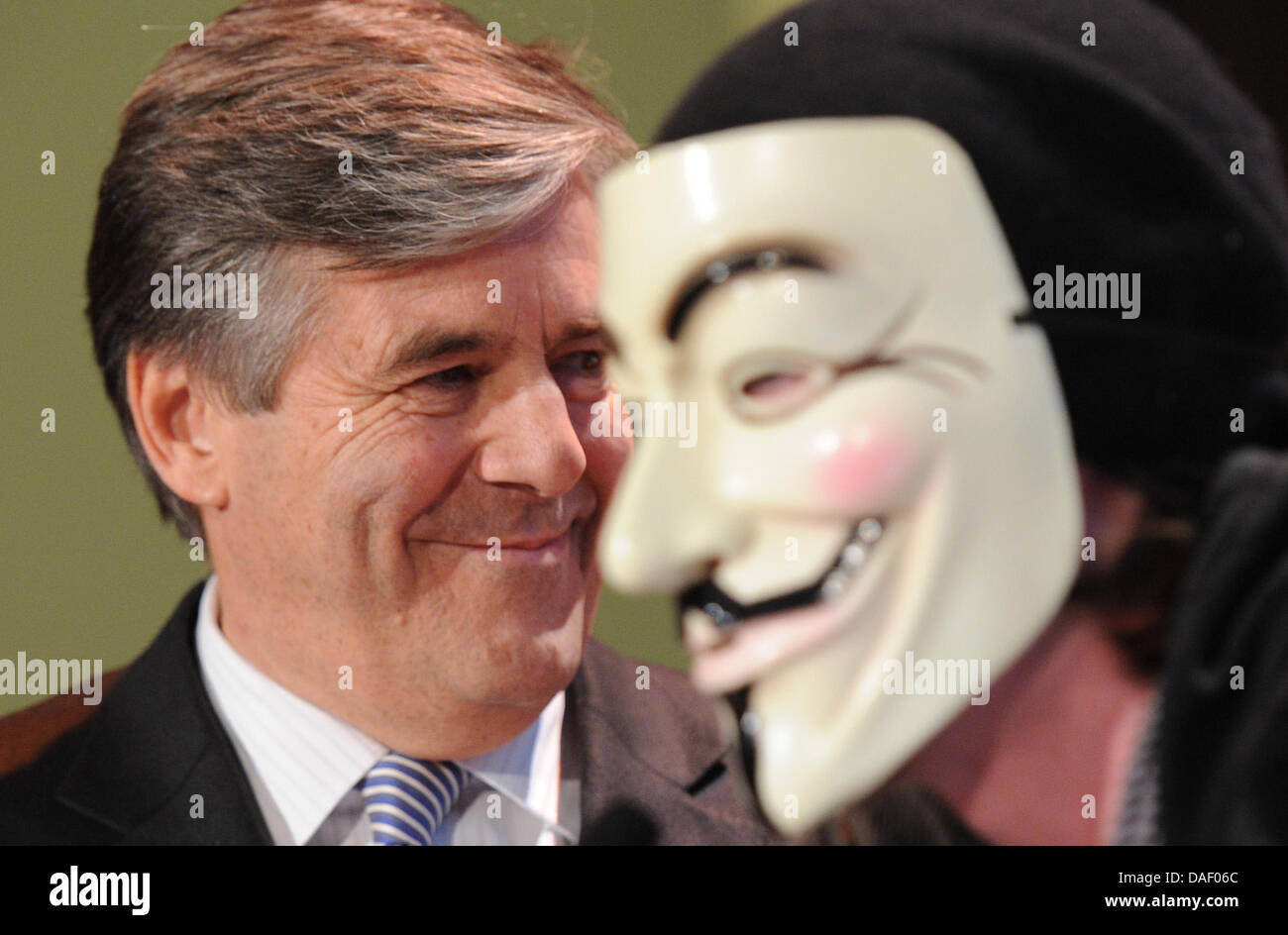 An Occupy activist wearing a Guy Fawkes mask interrupts Joseph Ackermann, CEO of Deutsche Bank, during his speech to the members' meeting of the Ehrbarer Kaufmann (Honorable Merchants) in Hamburg, Germany, 22 November 2011. Several activists of the Occupy movement disrupted the speech of the bank chief and stormed the podium at the chamber of commerce in Hamburg. Photo: MARCUS BRAN Stock Photo