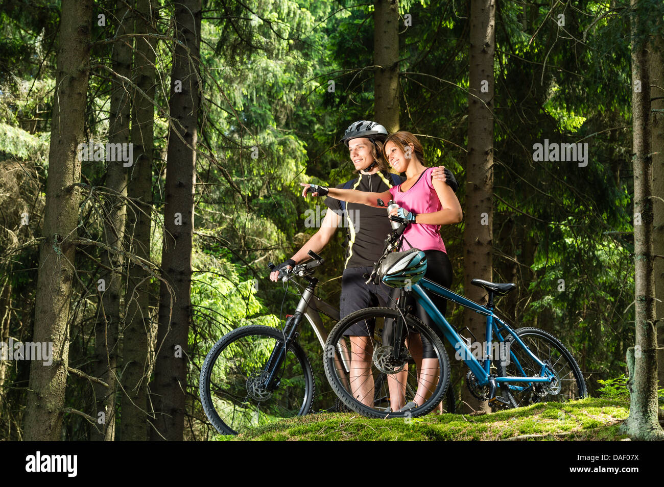 Smiling teen cyclists pointing and standing Stock Photo