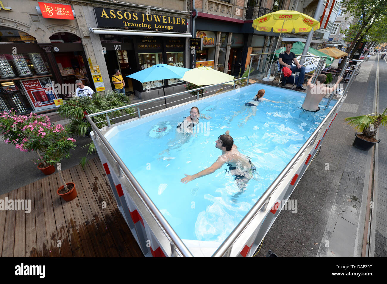 Karlsruhe, Germany. 11th July, 2013. People go for a swim in a mobile container pool in Karlsruhe, Germany, 11 July 2013. An intermodal container was converted into a swimming pool as part of a marketing strategy to increase popularity of the eastern Kaiserstrasse, which is currently blocked due to construction works. Photo: Uli Deck/dpa/Alamy Live News Stock Photo