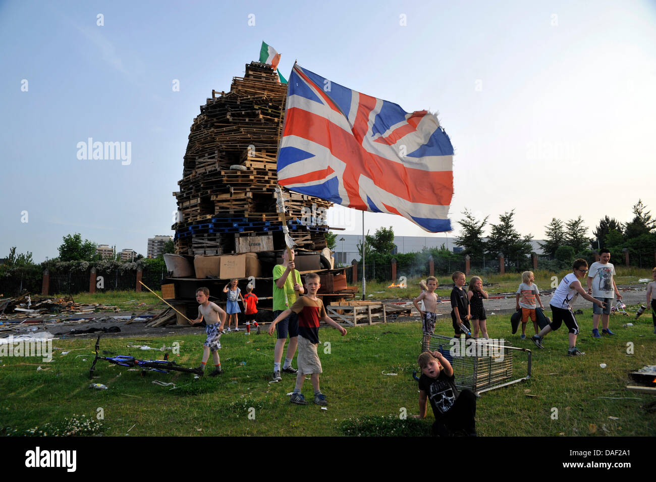 Belfast, Northern Ireland. 11th July, 2013. On July 11, 'Eleventh Night' bonfires are lit in staunchly Protestant areas. Many are massive constructions of wooden pallettes, old sofas and rubber tyres topped with Irish flags or effigies of pro-Nationalist figures. Bonfire architects battle it out to see who can build the biggest, and shifts of young guardians ensure rival builders don't steal their burnable booty. At midnight the bonfires are set alight, and these raging infernos can be seen blazing across the city. Pictured:  Falls Road and The Shankhill Credit:  andrew chittock/Alamy Live New Stock Photo