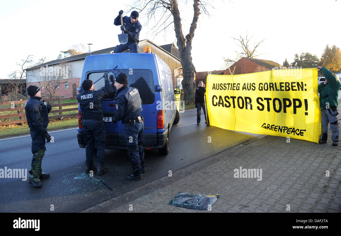Police officers try to open a van of anti-nuclear activists from the environmental group Greenpeace during a protest action against the castor transport in  Klein Gusborn, Germany, 28 November 2011. The Greenpeace activists moored with the street to block the southern castor transport route. The 13th Castor transport with German nuclear waste is expected in Wendland from the reproc Stock Photo