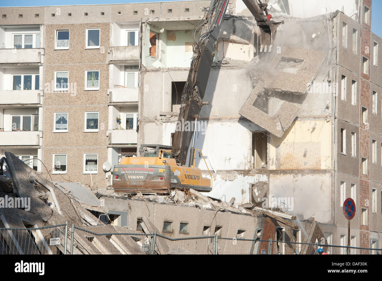 An excavator tears down a GDR highrise in Stralsund, Germany, 28 November 2011. The Stralsund housing association starts to deconstruct its apartment blocks. The federal government funds the demolition of 64 units as part of the 'Urban Redevelopment East' development programme. The block seen in the picture will be auctioned. The block from 1978 belongs to the federal government an Stock Photo