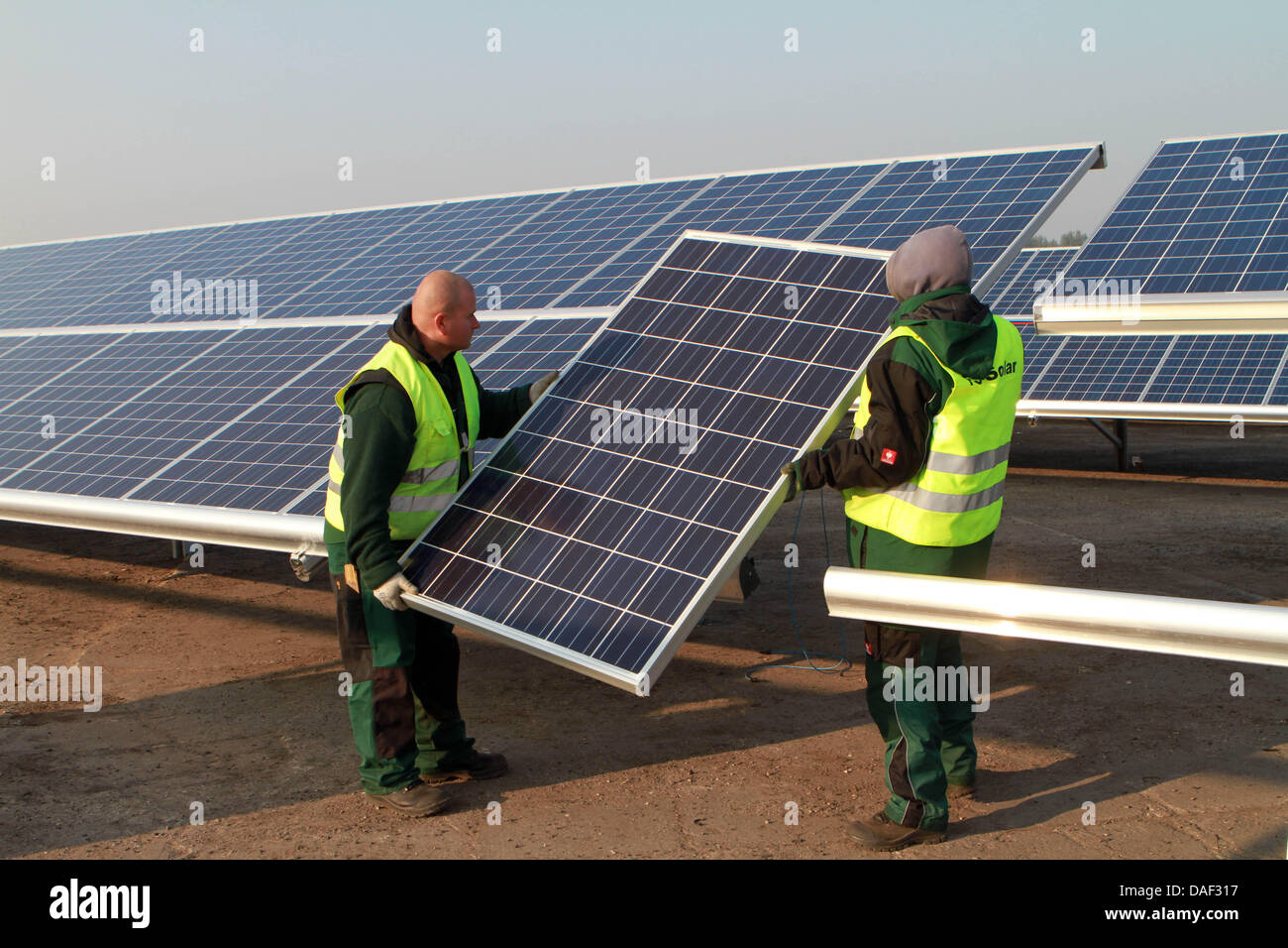 Workers set up solar modules for the solar park at the former Staaken Airport in Dallgow-Doeberitz, Germany, 14 November 2011. In December 2011, the Saferay facility is to produce electricity for the first time. 21 megawatts per year will be produced on the 65-hectares area. Photo: Nestor Bachmann Stock Photo