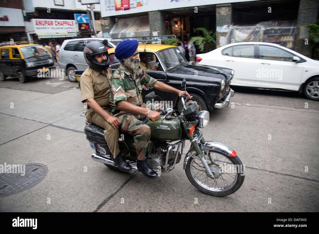 Sikh on motorbike riding past Leopold's Cafe Colaba Mumbai  famous in the novel Shantaram Stock Photo