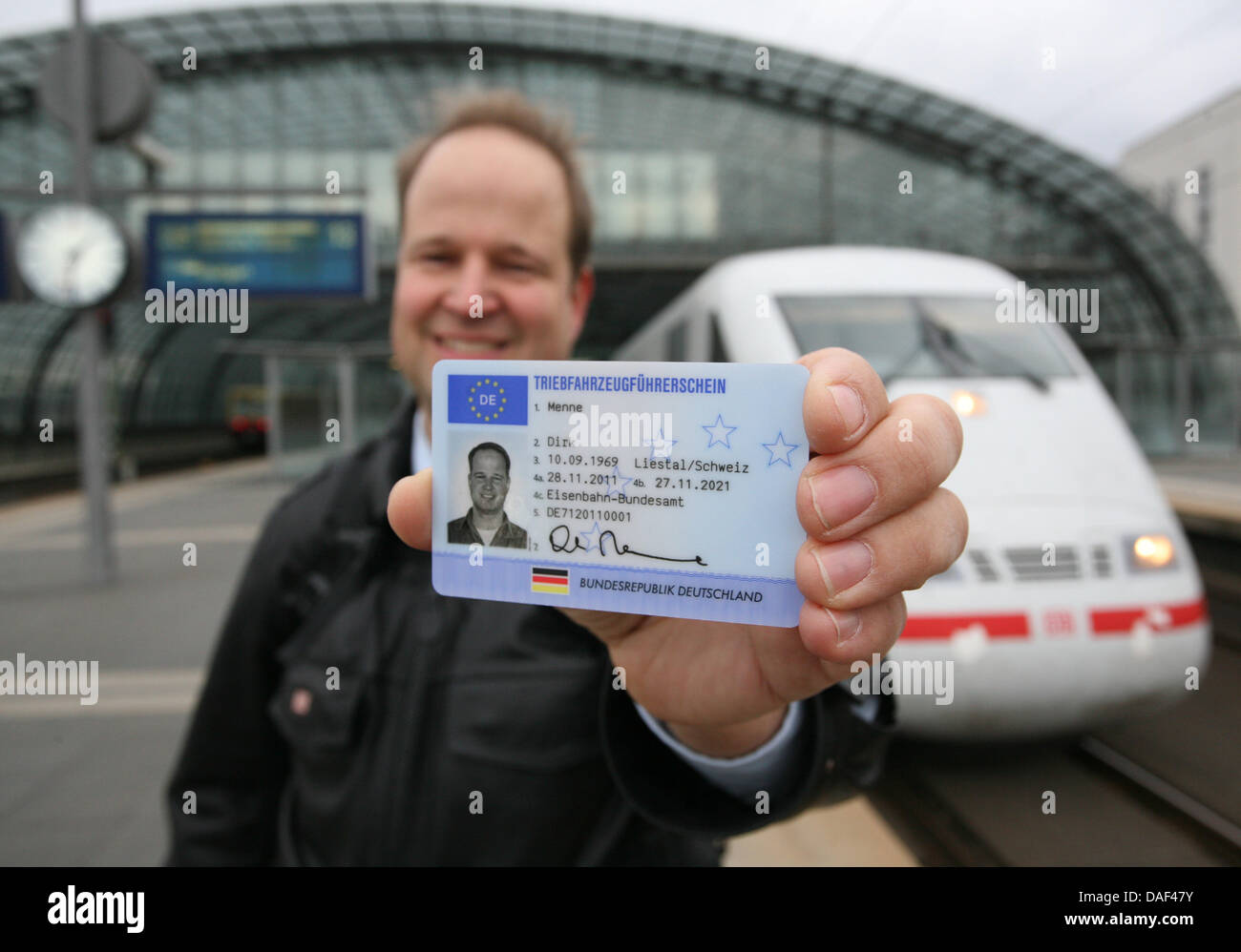 Train driver Dirk Menne presents his train licence in front of an ICE train at Central Station