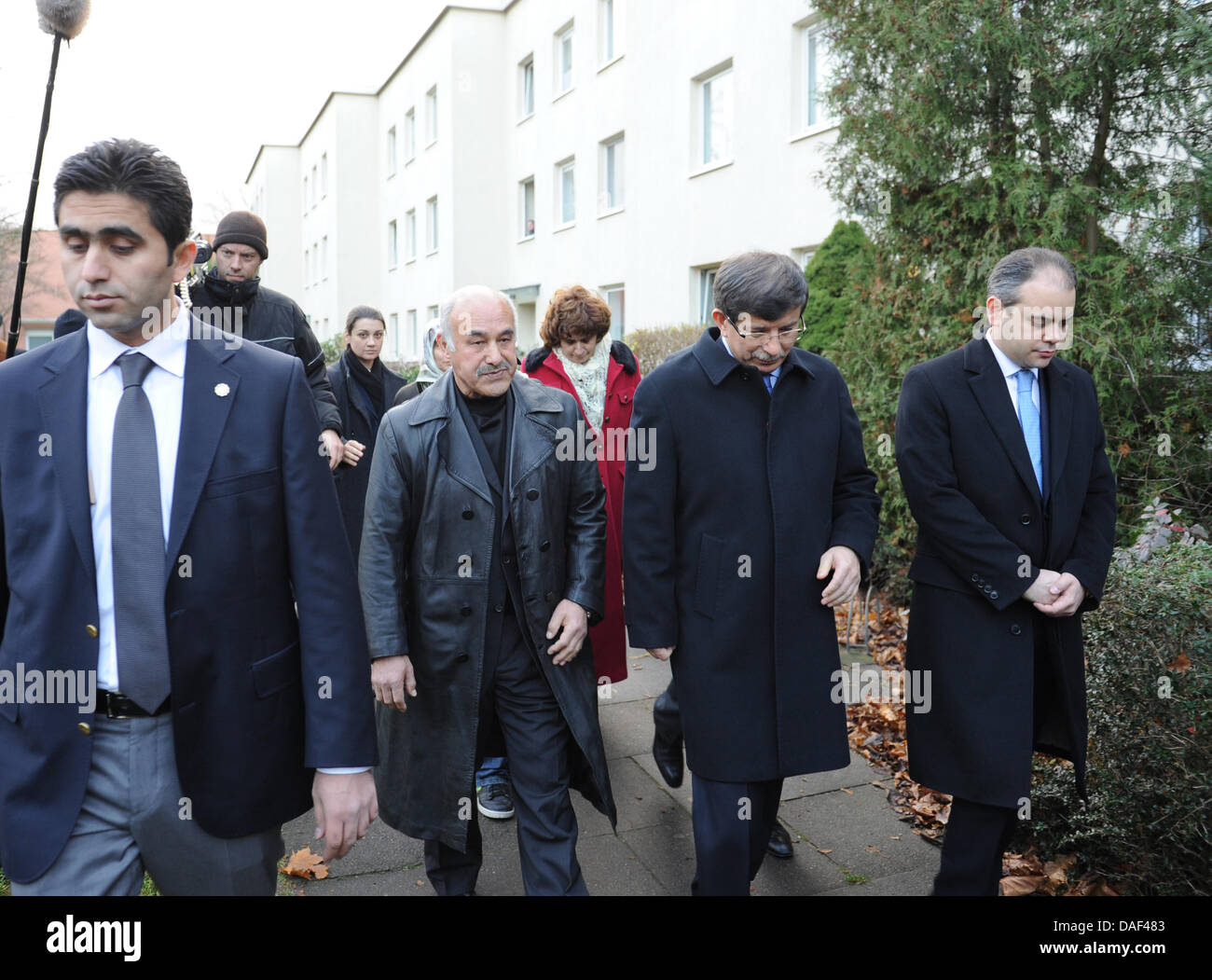 The Turkish Foreign Minister Ahmet Davutoglu (2-R) and Ali Taskopru (C), father of a vegetable seller murdered in 2001, walk past the victim's house in Hamburg, Germany, 01 December 2011. During his trip through Germany, Davutoglu visits several family members of victims of the Zwickau-based neo-Nazi terror cell. In his four-day-trip, Davutoglu will also visit Wiesbaden, Frankfurt, Stock Photo