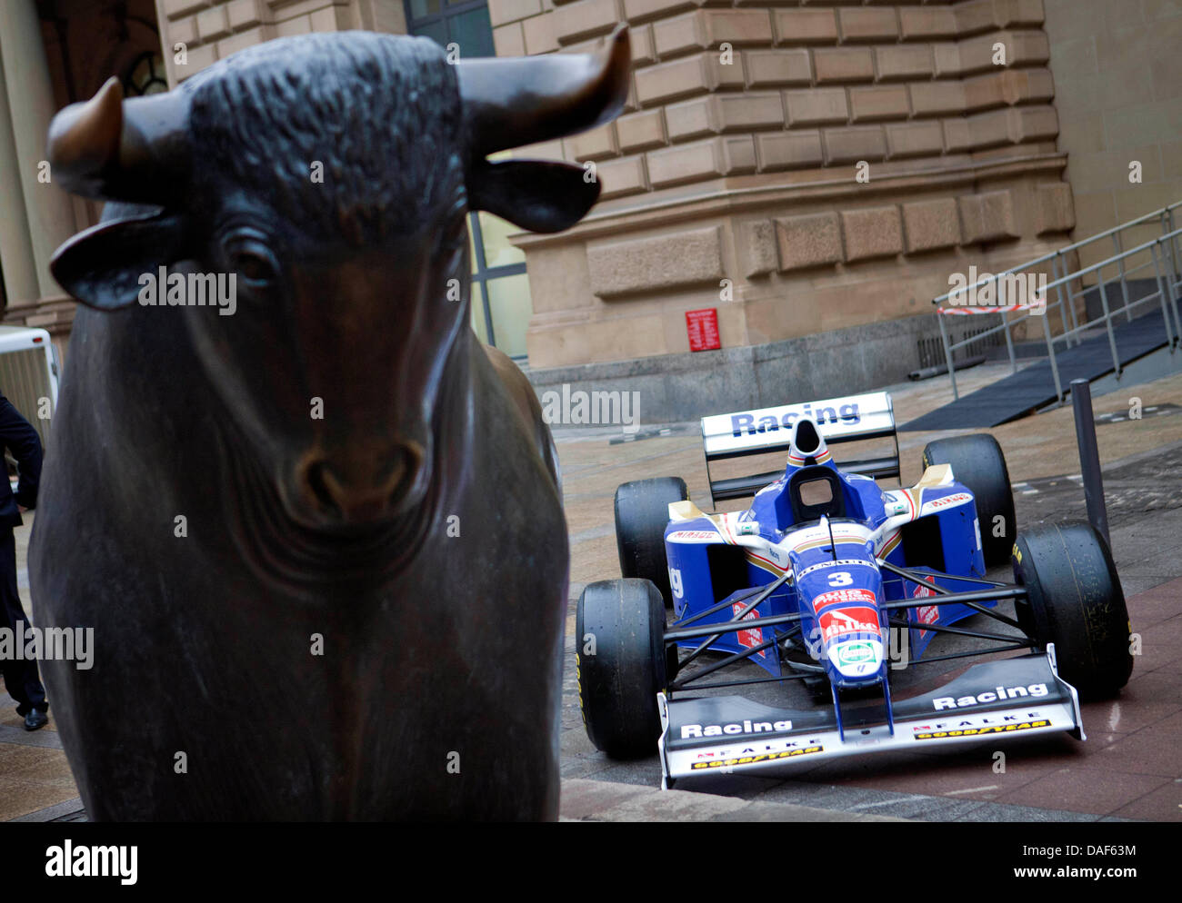 A bronze sculpture of a bull and a Formula One race car are situated in ...