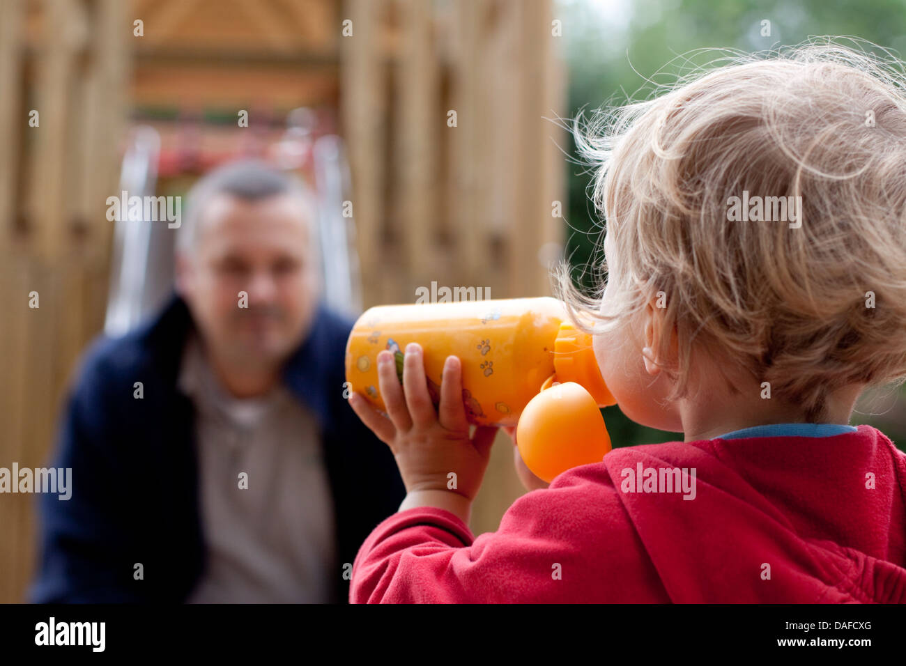 Germany, Girl drinking from bottle, father in background Stock Photo