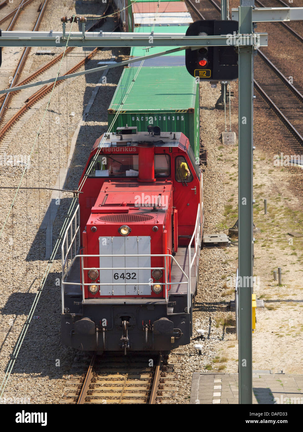 Red of a long freight cargo train loaded with containers photographed in Breda, the
