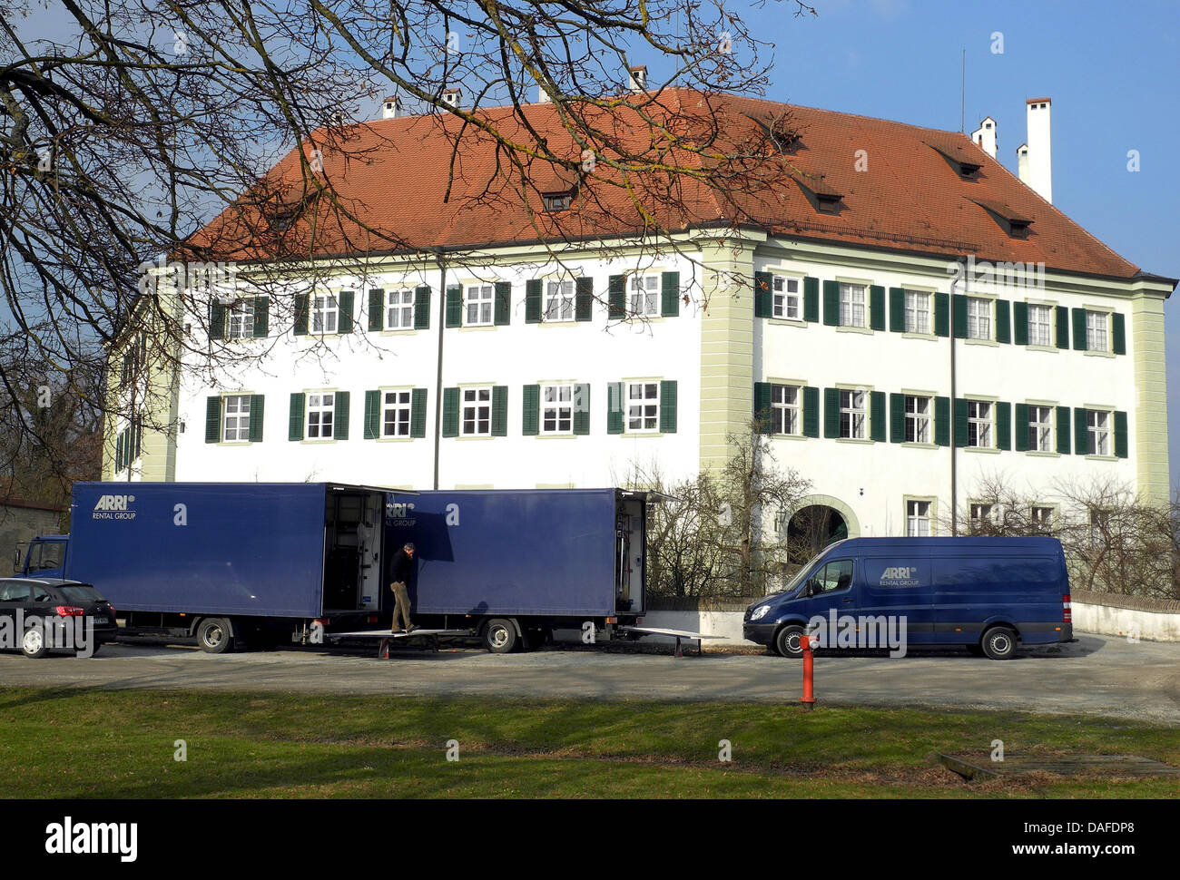 A picturesque view with blue film trucks stands in front of the manor house  in Suenching, Germany, 22 February 2011. The manor house serves as the  backdrop of a period picture starring