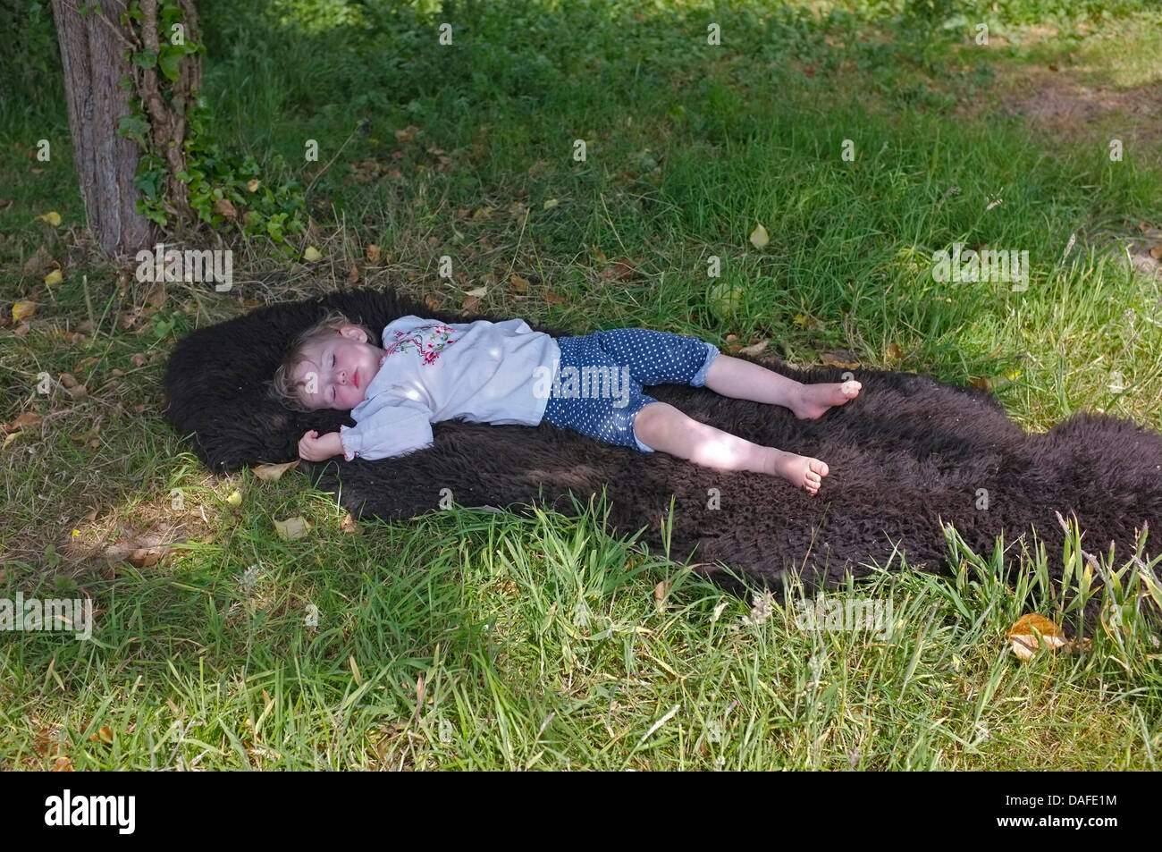 A two year old girl asleep in the shade Stock Photo