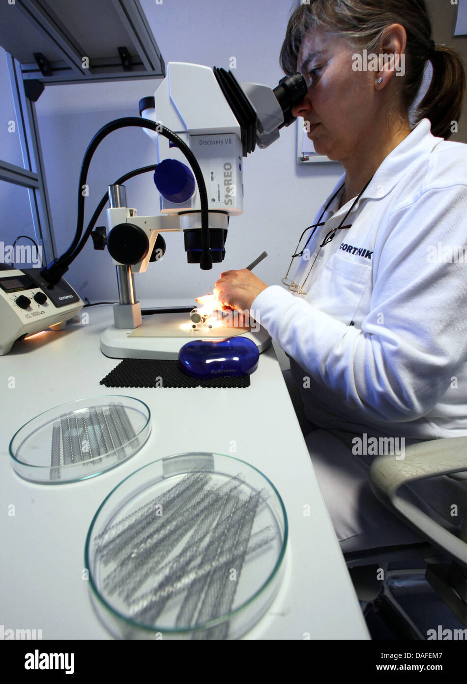 A member of staff examines a flexible stent through a microscope at a ...
