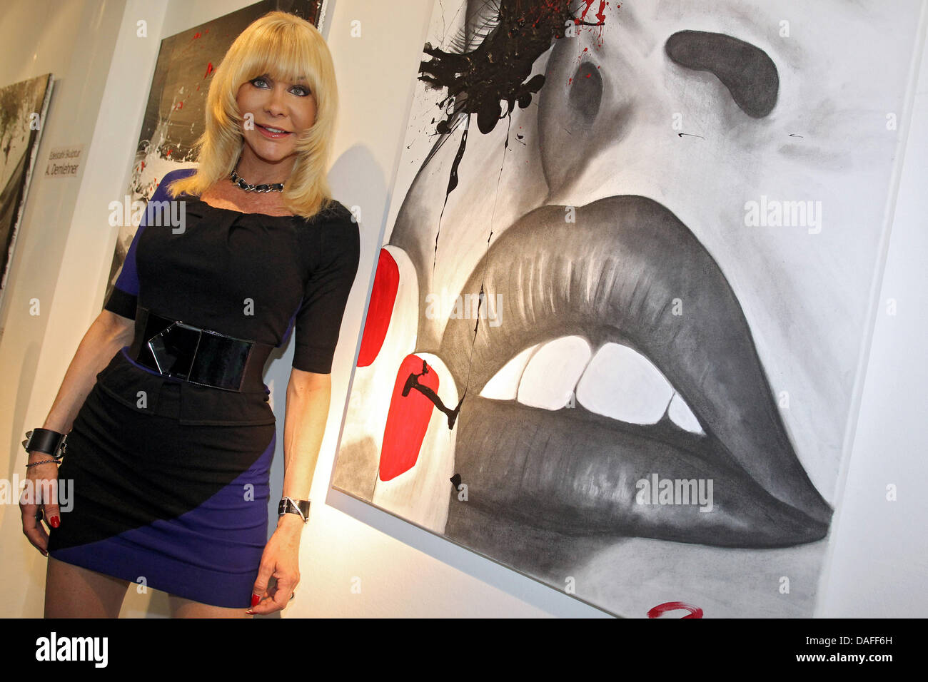 Former pornstar Nora Dvorak aka Dolly Buster smiles next to her painting 'Shooting' (R) during the vernissage of her exhibition in Fuerth, Germany, 24 February 2011. A total of 31 paintings by Dolly Buster are on display in the exhibition. Photo: Daniel Karmann Stock Photo