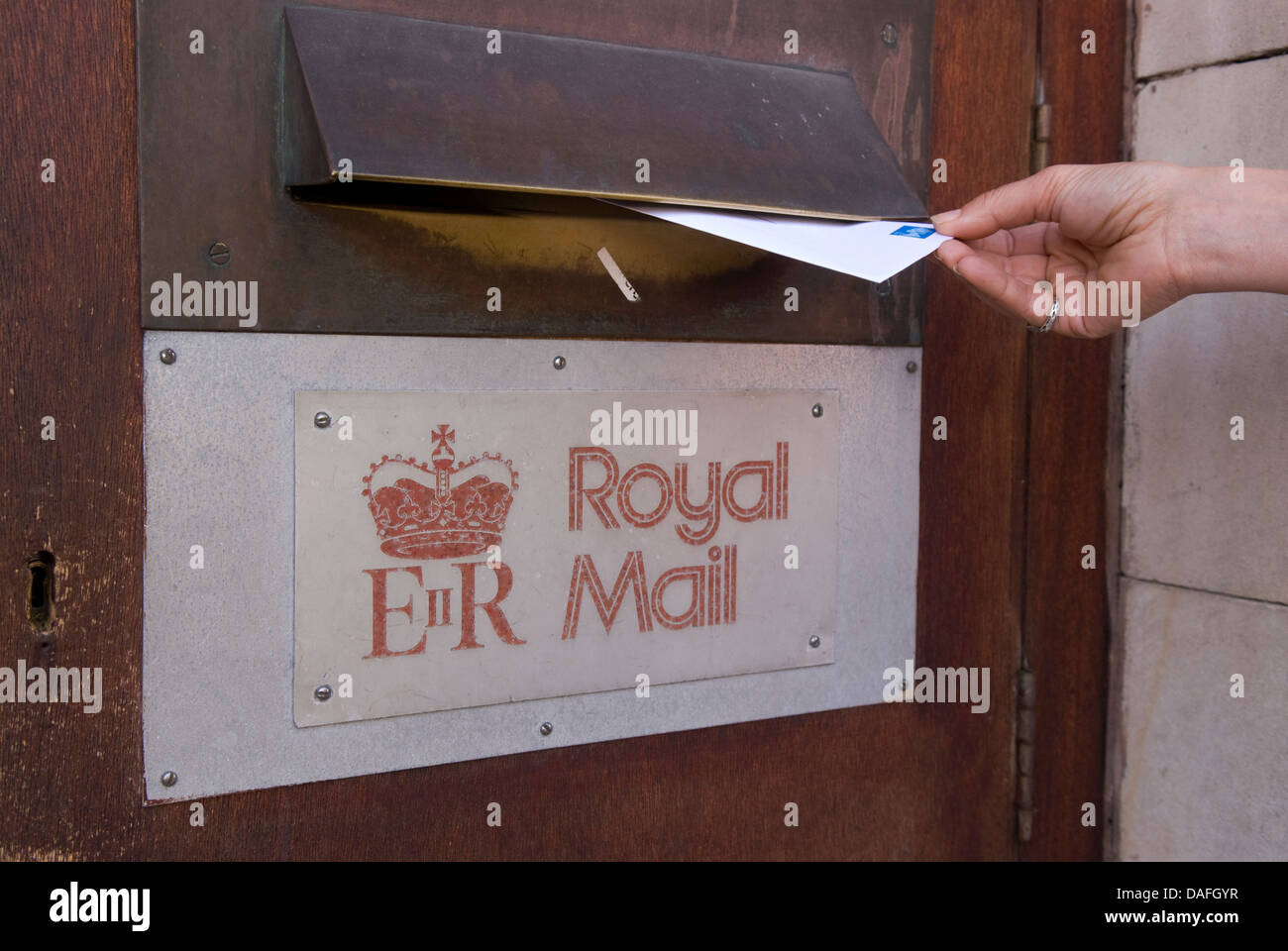 Woman posting a second class letter in main post office, Petersfield, Hampshire, UK. Stock Photo