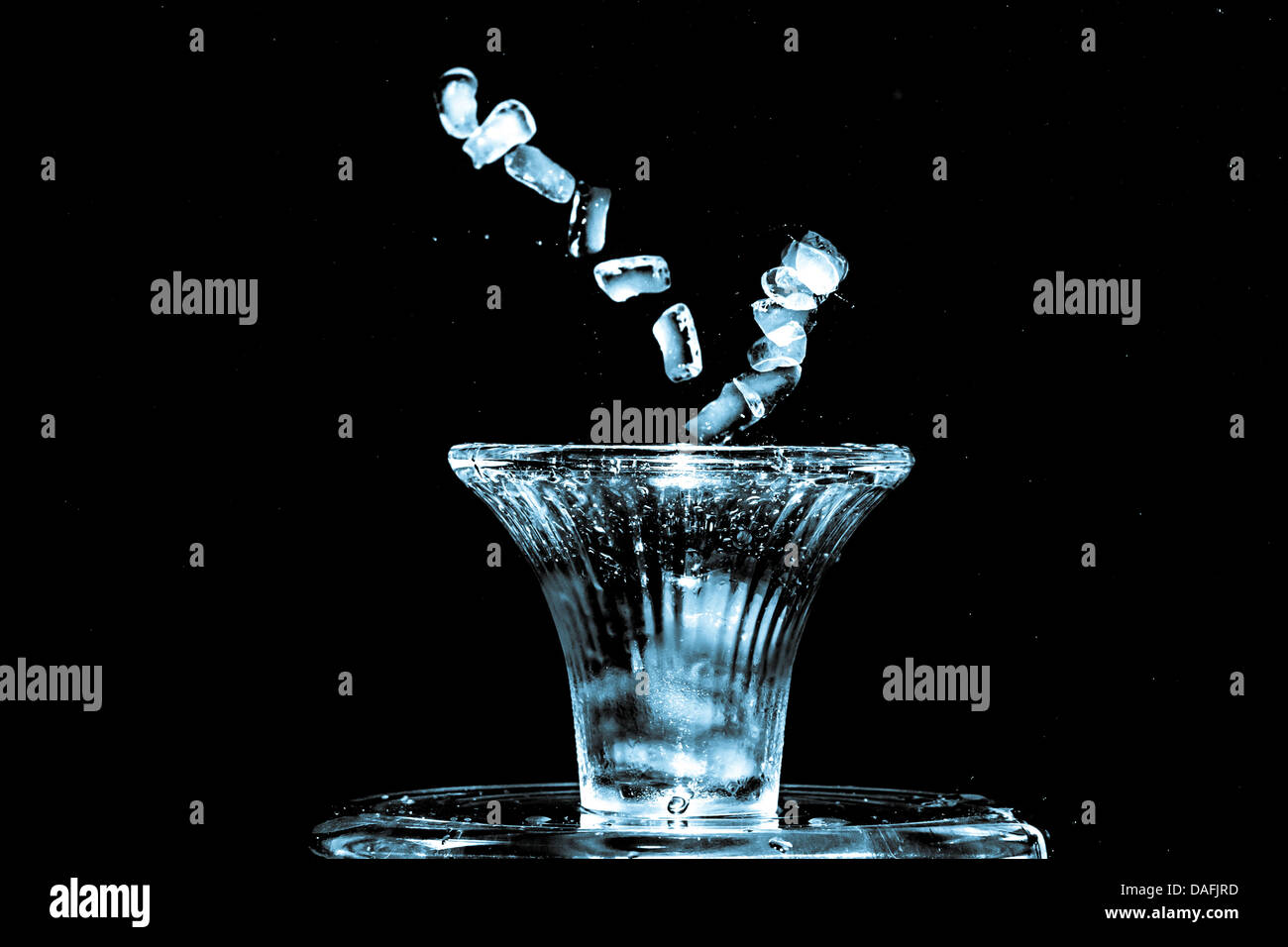 Stroboscopic effect created using flash capturing the motion ice as it splashes into a glass Stock Photo