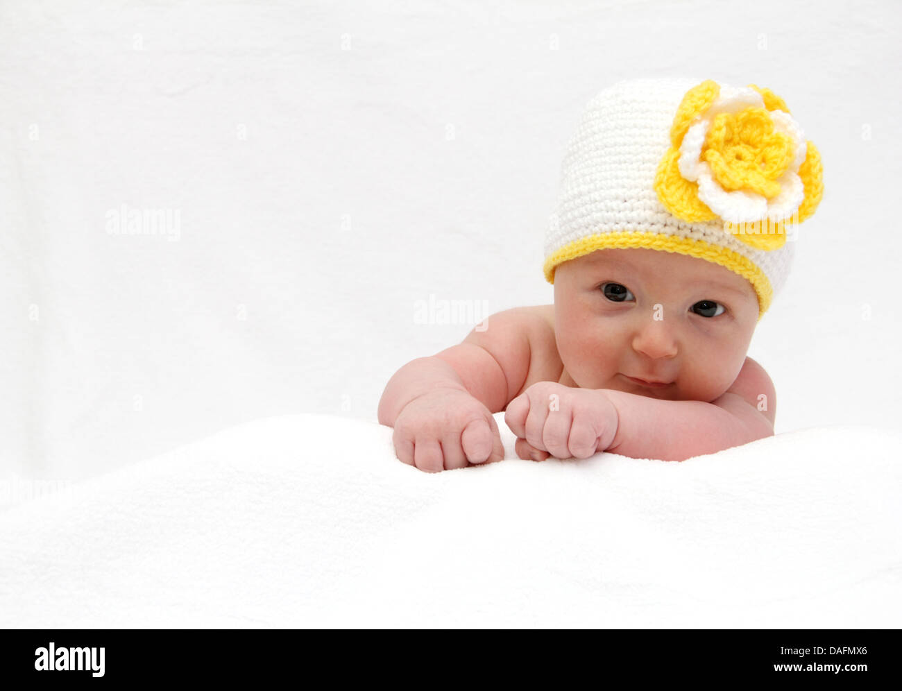 Baby with a knitted white hat baby on stomach Stock Photo
