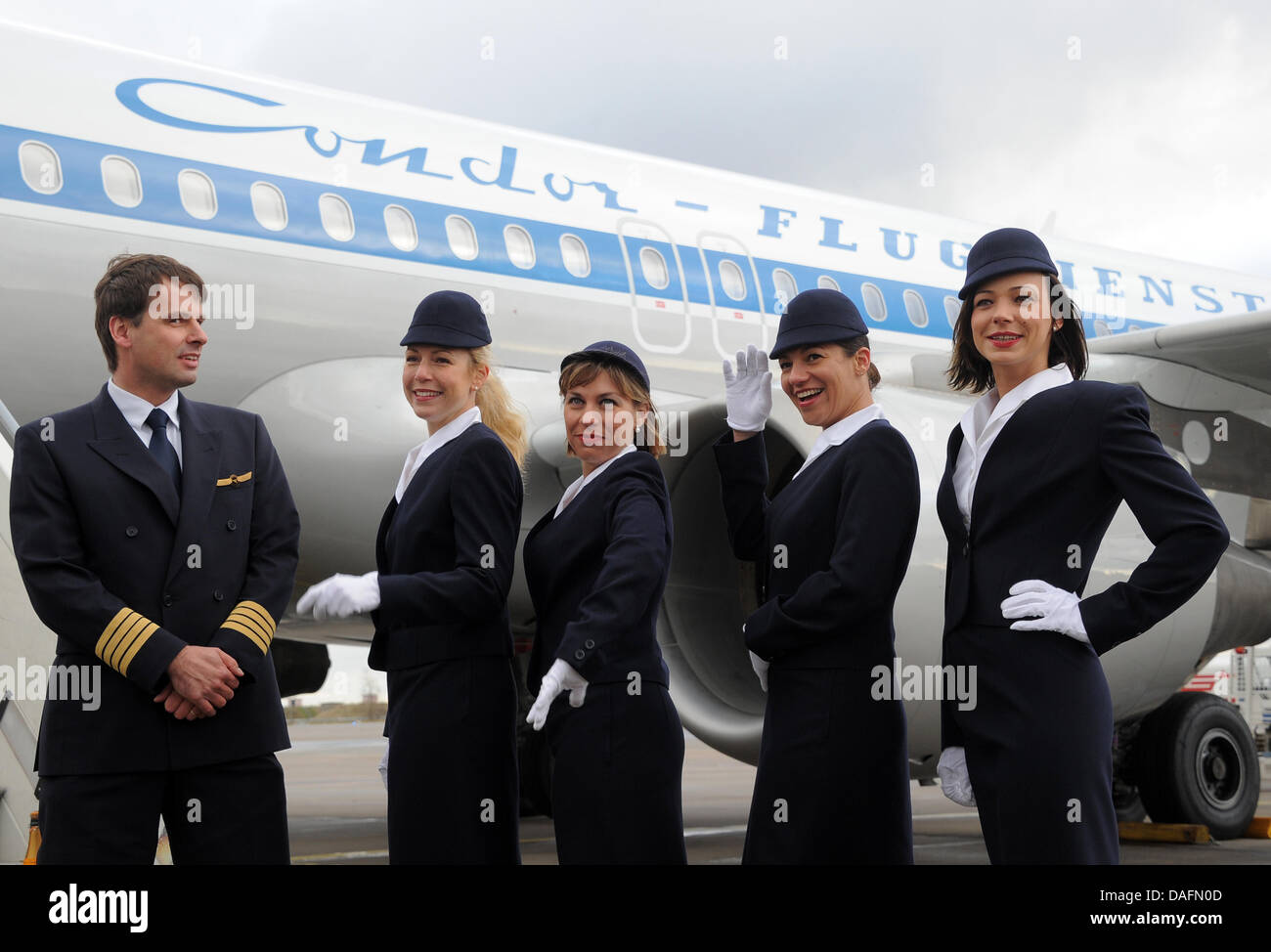 Captain Karl-Peter Ritter (L) and four flight attendants stand in front of a special retro-style Condor aircraft at the aiport in Schoenefeld, Germany, 05 December 2011. The airline calls the plane 'Hans' in honour of the founder of Geisler Tours that chartered the first Condor (Deutsche Flugdienst) aircraft in 1956. Photo: Bernd Settnik Stock Photo