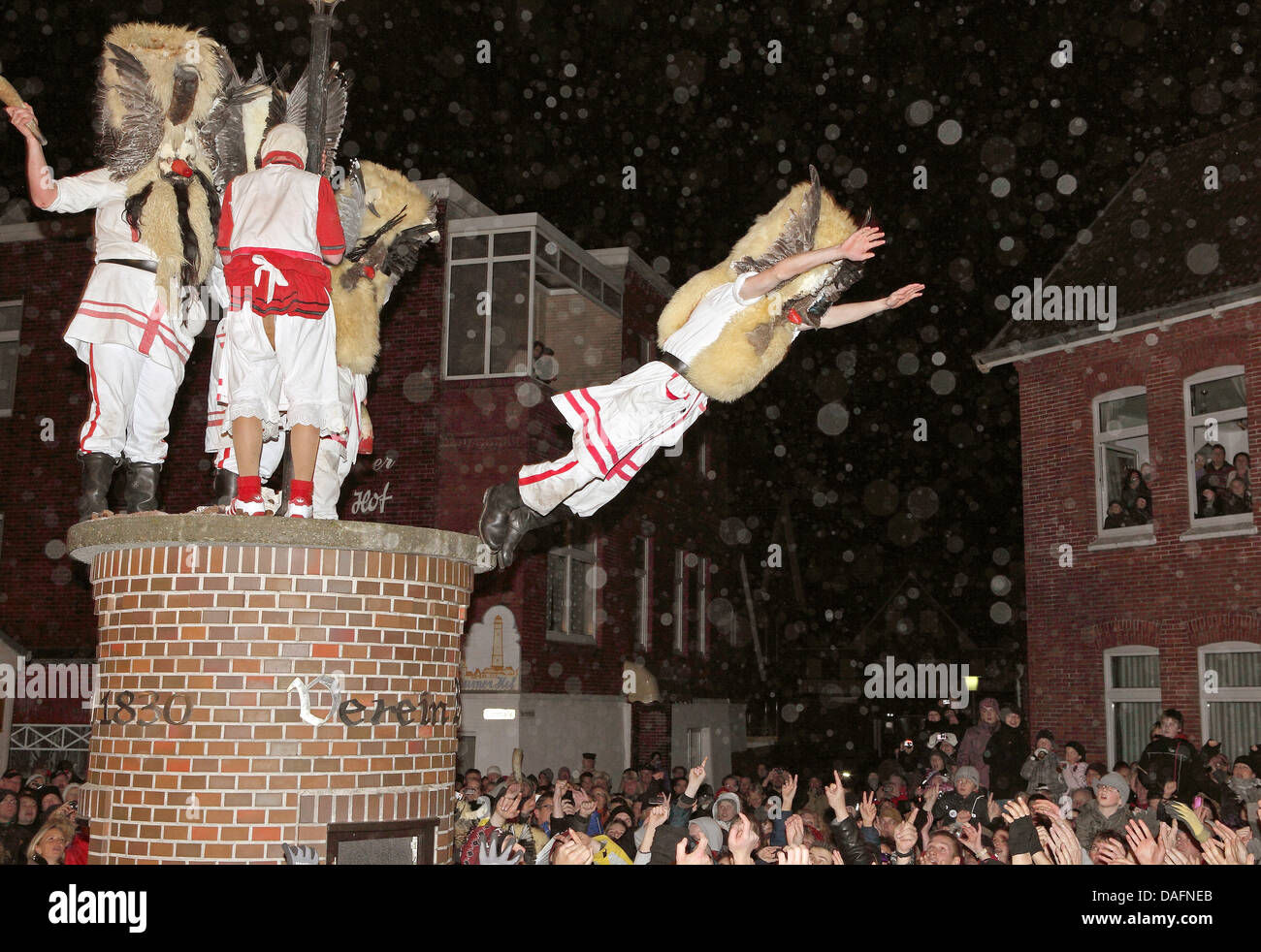 Masked men from a men's club jump from a column into the arms of spectators on the North Sea island of Borkum, Germany, 05 December 2011. The daring jump into the mass of people could be watched during the traditional Klaasohm festival. Previously, the six bachelors took to the streets with their entourages. Photo: Reinhold Grigoleit Stock Photo