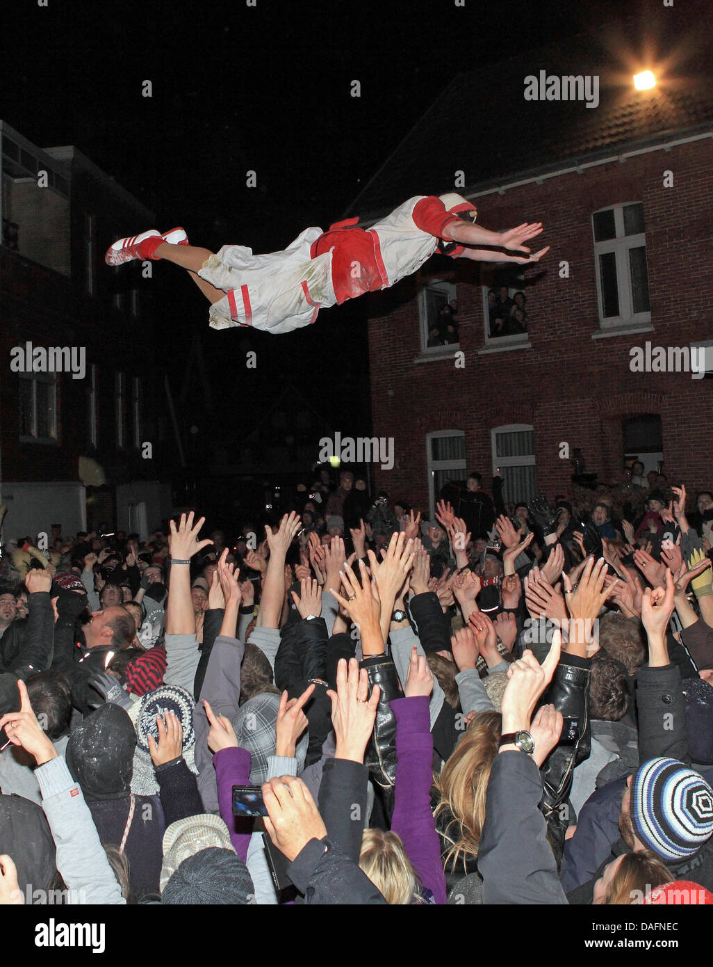 Masked men from a men's club jump from a column into the arms of spectators on the North Sea island of Borkum, Germany, 05 December 2011. The daring jump into the mass of people could be watched during the traditional Klaasohm festival. Previously, the six bachelors took to the streets with their entourages. Photo: Reinhold Grigoleit Stock Photo