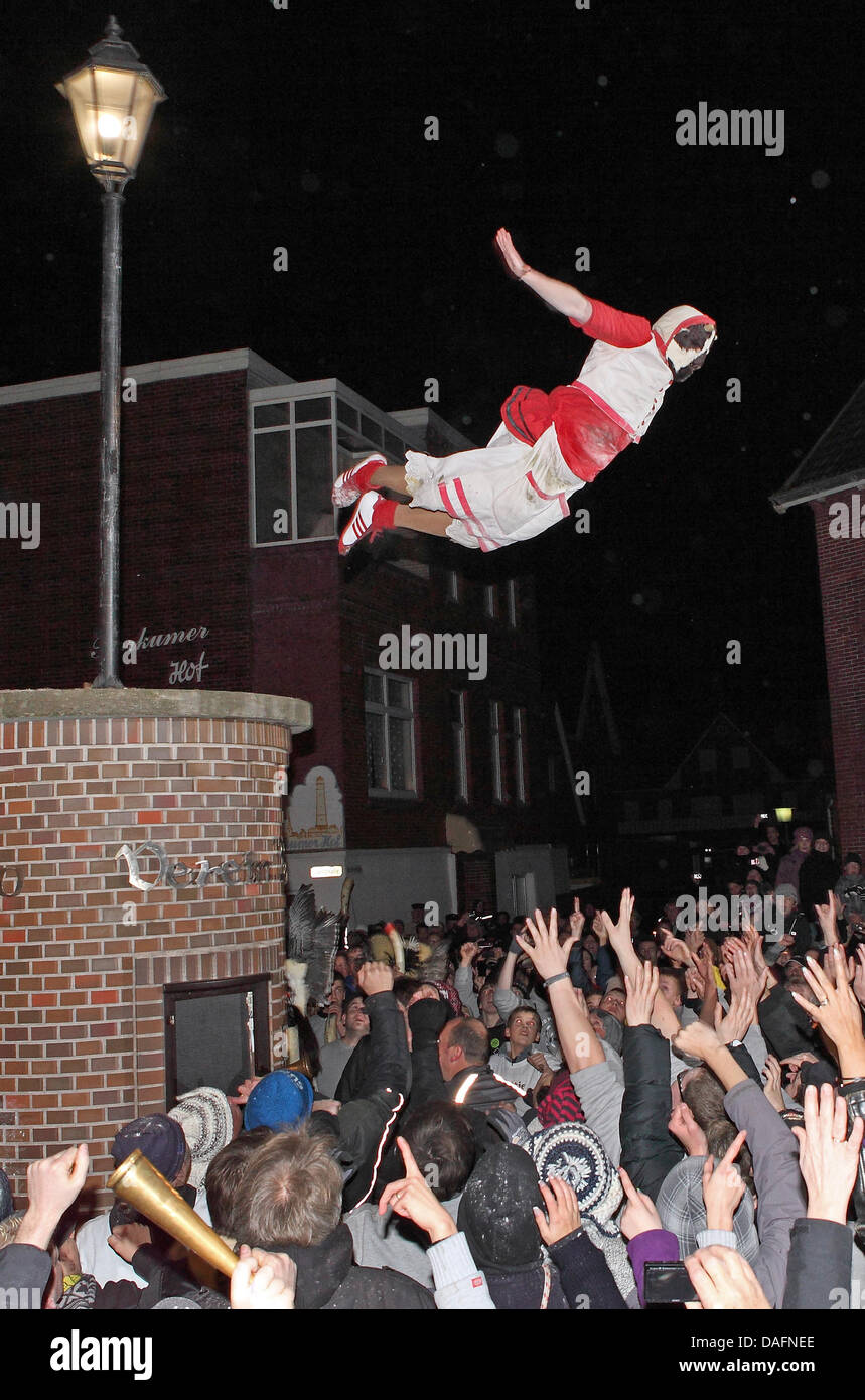 Masked men from a men's club jump from a column into the arms of spectators on the North Sea island of Borkum, Germany, 05 December 2011. The daring jump into the mass of people could be watched during the traditional Klaasohm festival. Previously, the six bachelors took to the streets with their entourages. Photo: Reinhold Grigoleit Stock Photo