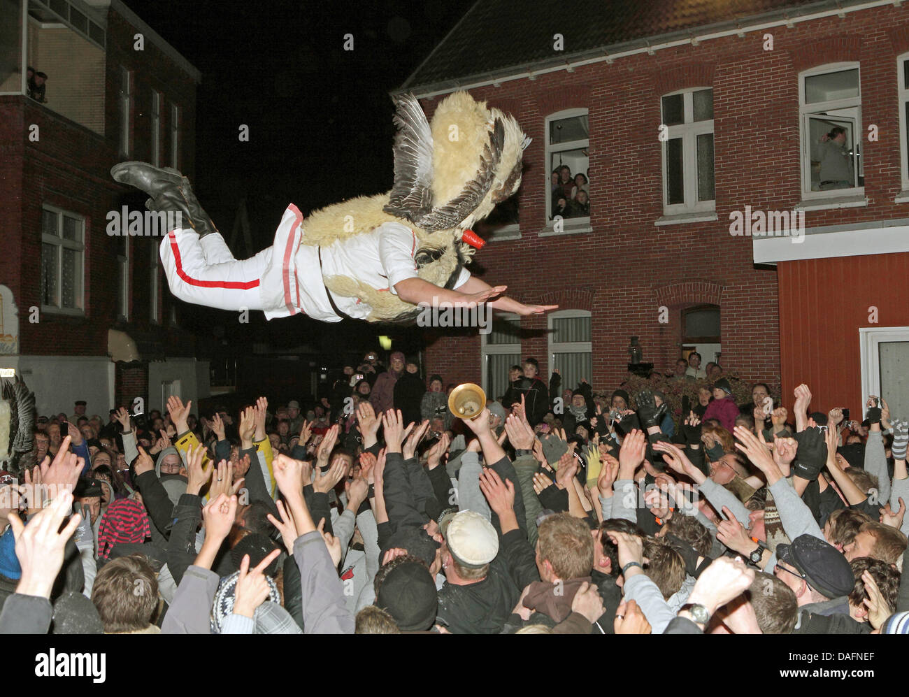 Masked men from a men's club jump from a column into the arms of spectators on the North Sea island of Borkum, Germany, 05 December 2011. The daring jump into the mass of people could be watched during the traditional Klaasohm festival. Previously, the six bachelors took to the streets with their entourages. Photo: Reinhold Grigoleit Stock Photo