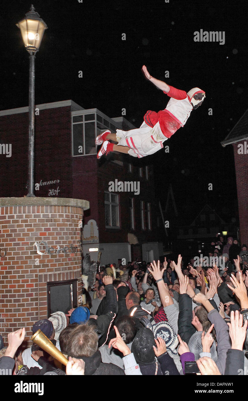 Masked men from a men's club jump from a column into the arms of spectators on the North Sea island of Borkum, Germany, 05 December 2011. The daring jump into the mass of people could be watched during the traditional Klaasohm festival. Previously, the six bachelors took to the streets with their entourages. Photo: Reinhold Grigoleit Stock Photo