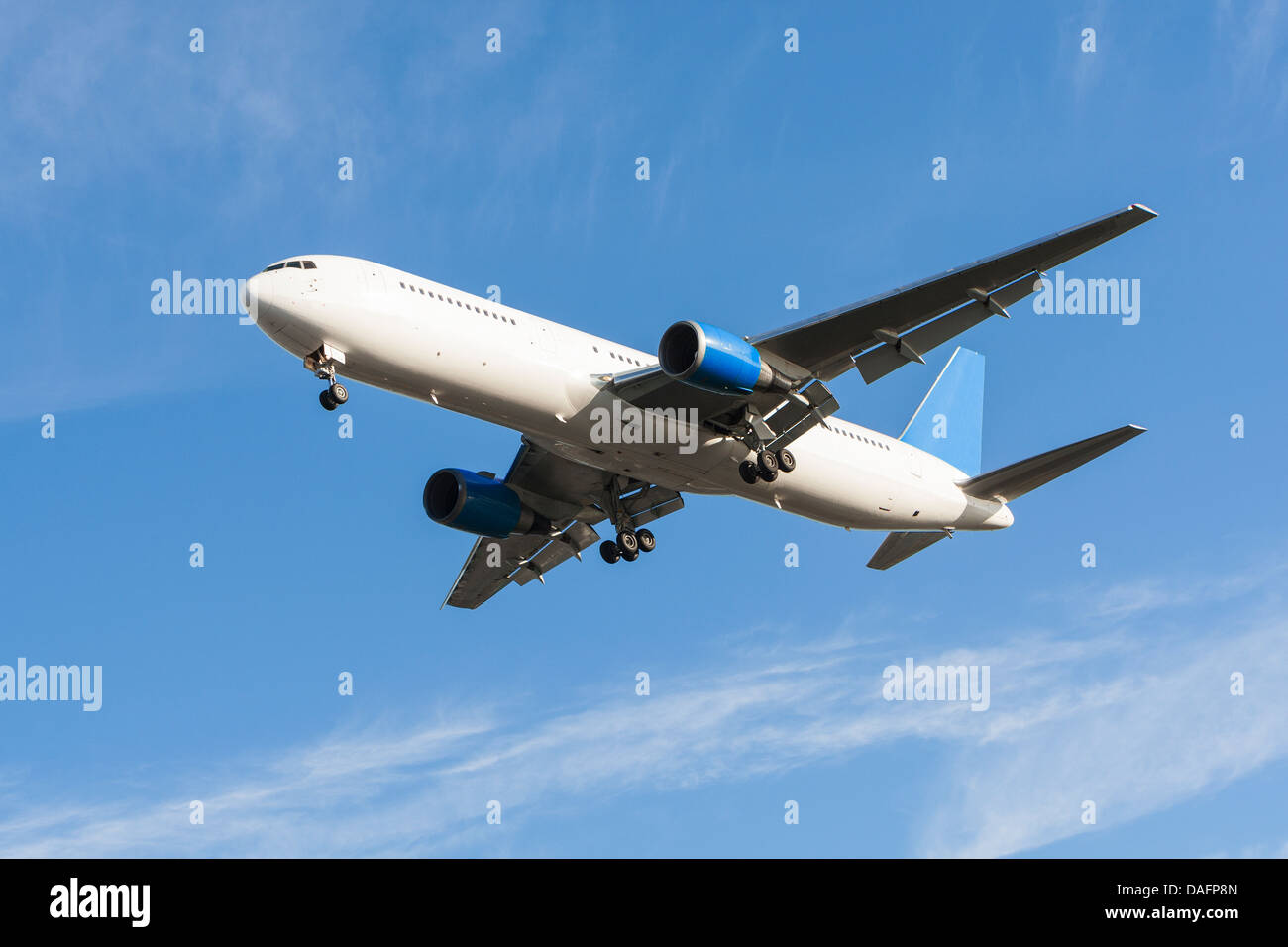 A generic airline airplane landing with undercarriage wheels and flaps down Stock Photo