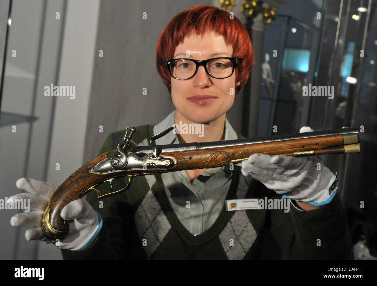 Museum employee Kathrin Stern presents an antique pistol from the 18th century of the arsenal of the Schwarzburg princes at Heidecksburg Palace in Rudolstadt, Germany, 08 December 2011. For four years, 4,000 armaments, harnesses, batons and thrustings had been restored with the help of the Federal Cultural Foundation. The latest restoration of the Schwarzburg arsenal makes it possi Stock Photo