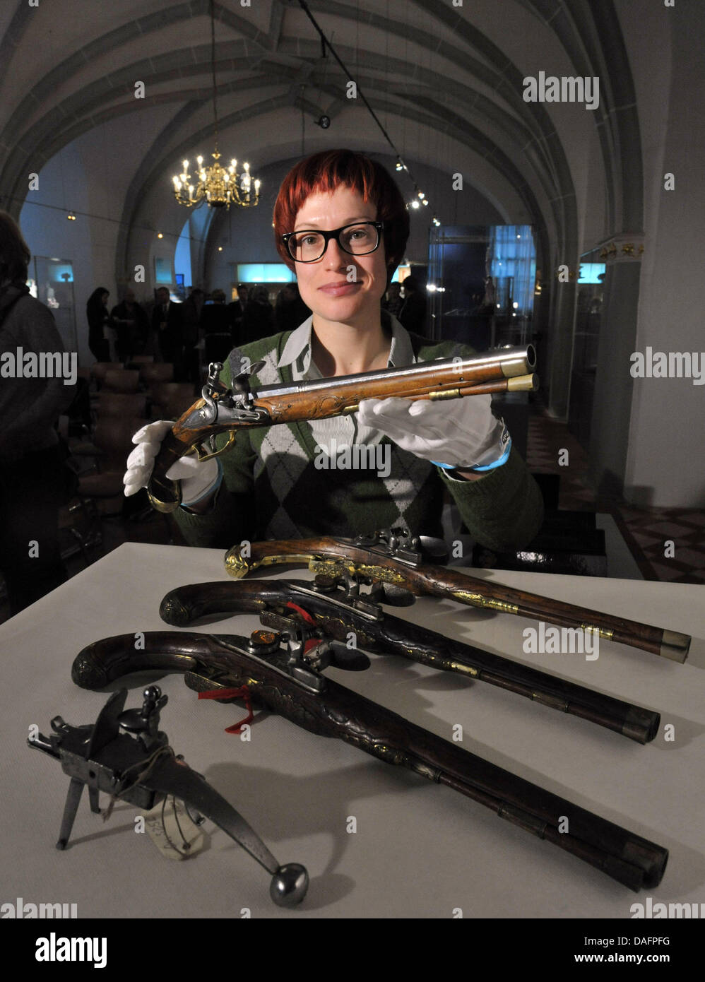 Museum employee Kathrin Stern presents an antique pistol from the 18th century of the arsenal of the Schwarzburg princes at Heidecksburg Palace in Rudolstadt, Germany, 08 December 2011. For four years, 4,000 armaments, harnesses, batons and thrustings had been restored with the help of the Federal Cultural Foundation. The latest restoration of the Schwarzburg arsenal makes it possi Stock Photo