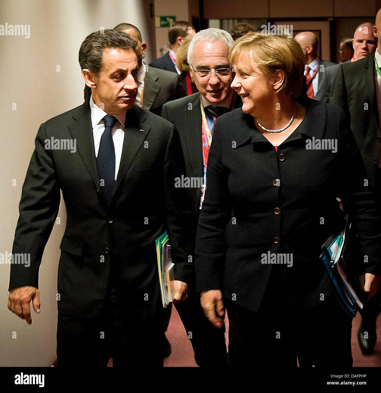 Bundeskanzlerin Angela Merkel (CDU, r) und Frankreichs Staatspräsident Nicolas Sarkozy (l) unterhalten sich in Brüssel, Belgien, auf dem Weg zum Arbeitsabendessen der Staats- und Regierungschefs am Donnerstag (08.12.2011) beim EU-Gipfel. In der mitte geht ein Dolmetscher. Merkel hatte vorher für eine Veränderung der EU-Verträge und für eine Stärkung der europäischen Institutionen g Stock Photo