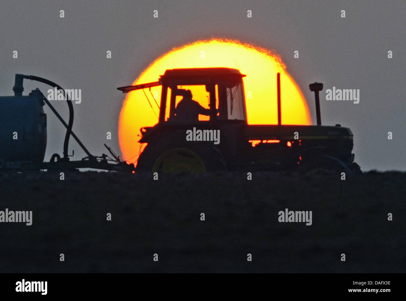 Ein Landwirt fährt am Mittwoch (23.02.2011) auf einem Acker nahe Feldkirchen (Niederbayern) mit seinem Traktor vor der aufgehenden Sonne. Foto: Armin Weigel dpa/lby Stock Photo