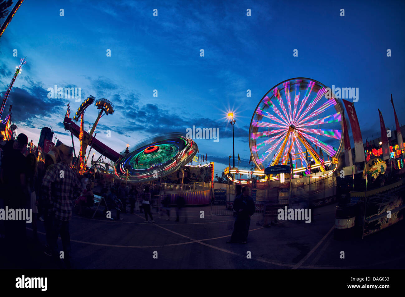 Calgary Stampede Amusement Rides; Ferris Wheel and Spinning Rides with lights on at dusk, just
