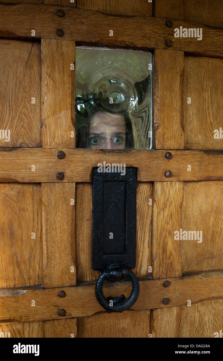 Terror Girl Looking Through The Glass Of A Front Door Stock Photo
