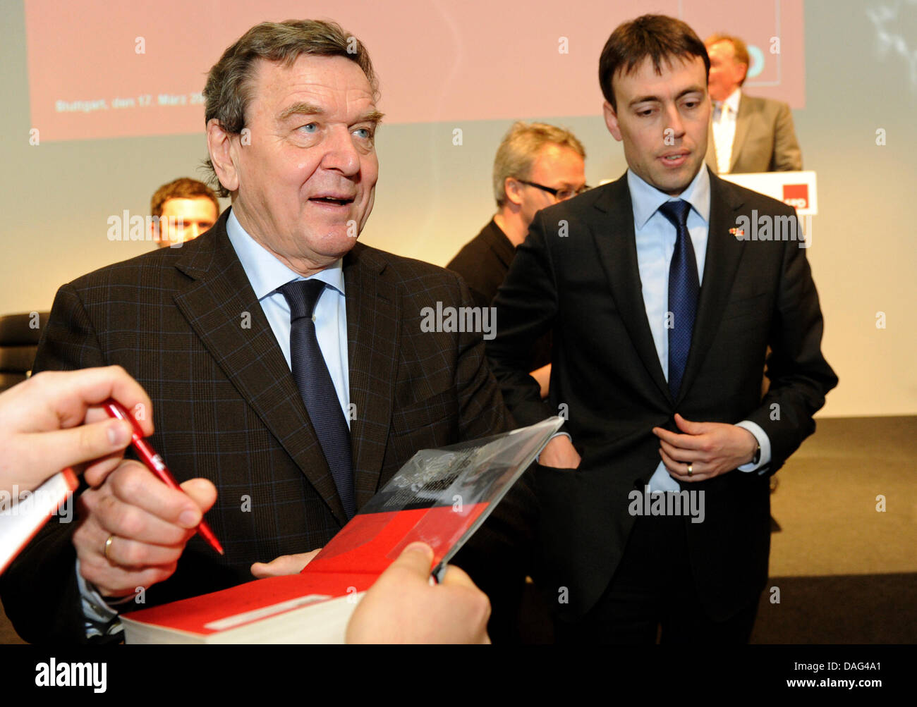Former German Chancellor Gerhard Schroeder (L-R) signs autographs next to SPD-top candidate for Baden Wuerttemberg's state election Nils Schmid at the Porsche Museum in Stuttgart, Germany, 17 March 2011. Schroeder visited an event of the Social Democratic Party with the title 'New Agenda for Baden-Wuerttemberg'. Photo: Marijan Murat Stock Photo