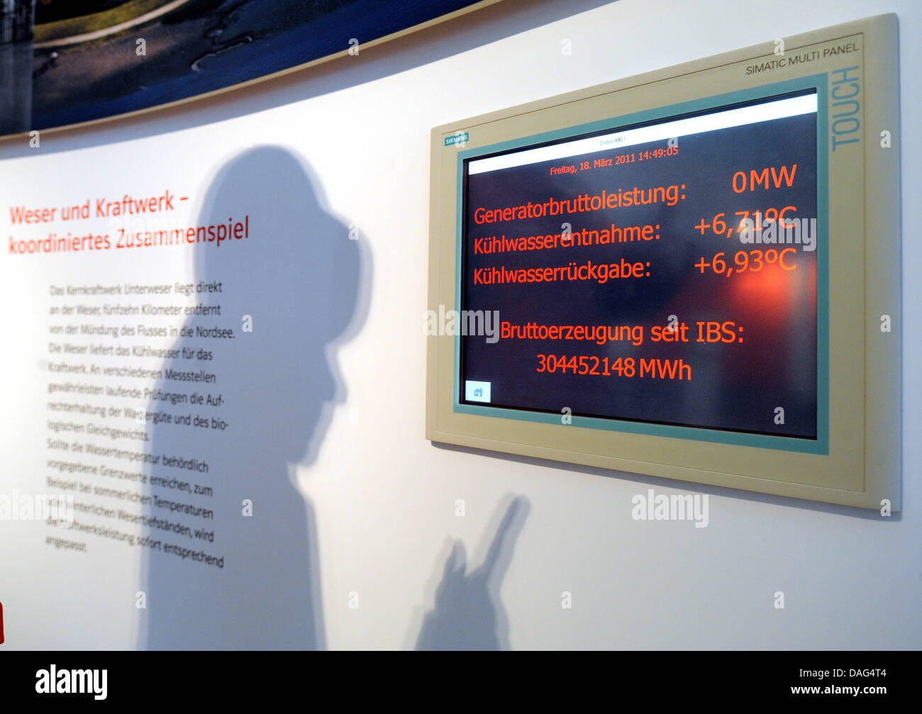 An engineer of energy company e.on points to the energy display in the communication center of the nuclear power station Unterweser in Esensham, Germany, 18 March 2011. The display shows that the general gross outpout is at zero megawatts, and that the temperature difference between the heat exchange water that is taken in and coming out of the reactor is very small. Lower Saxony's Stock Photo