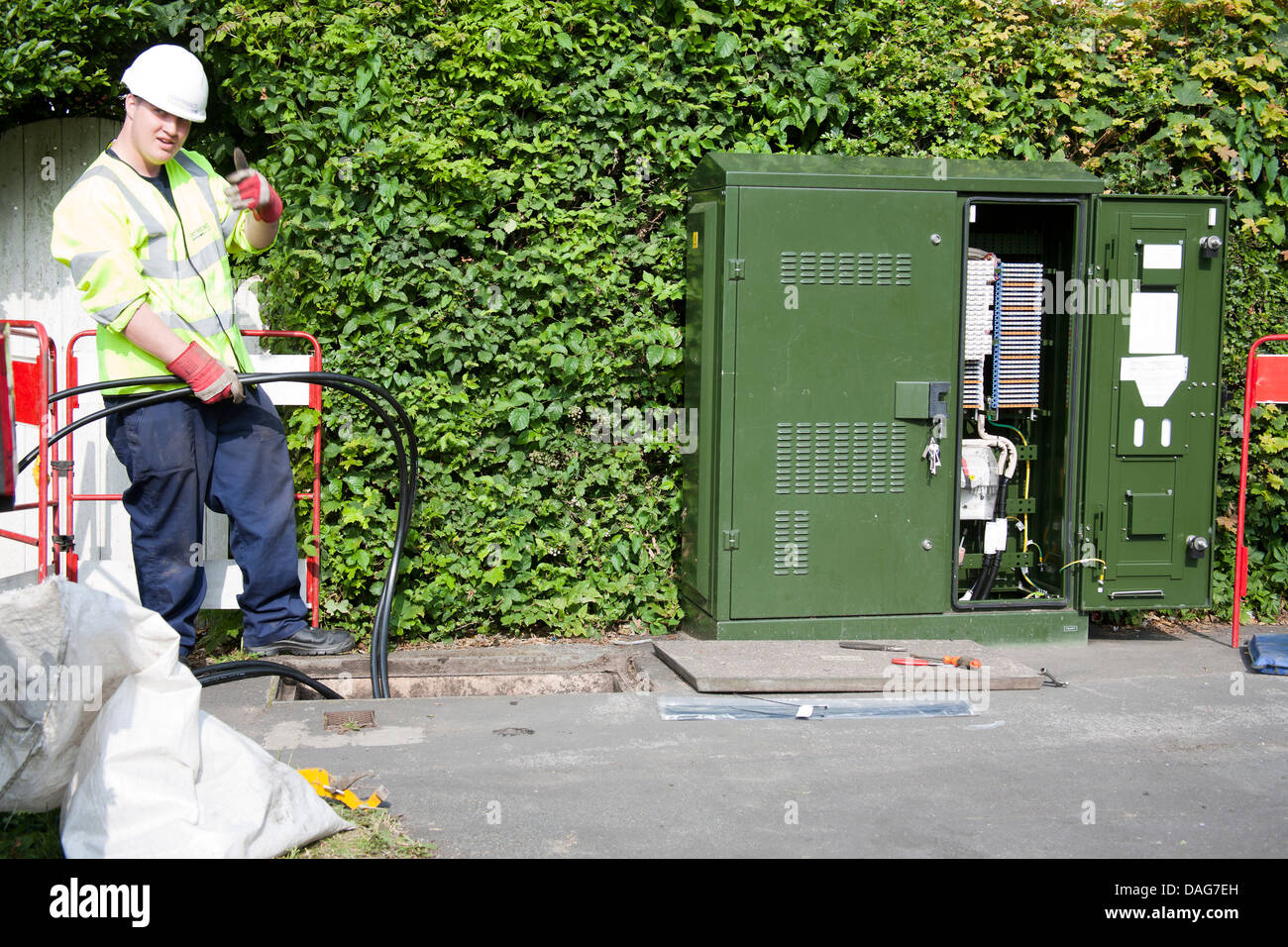 A BT Openreach telecommunications technician working in a manhole at the roadside, Southport, Merseyside, UK Stock Photo